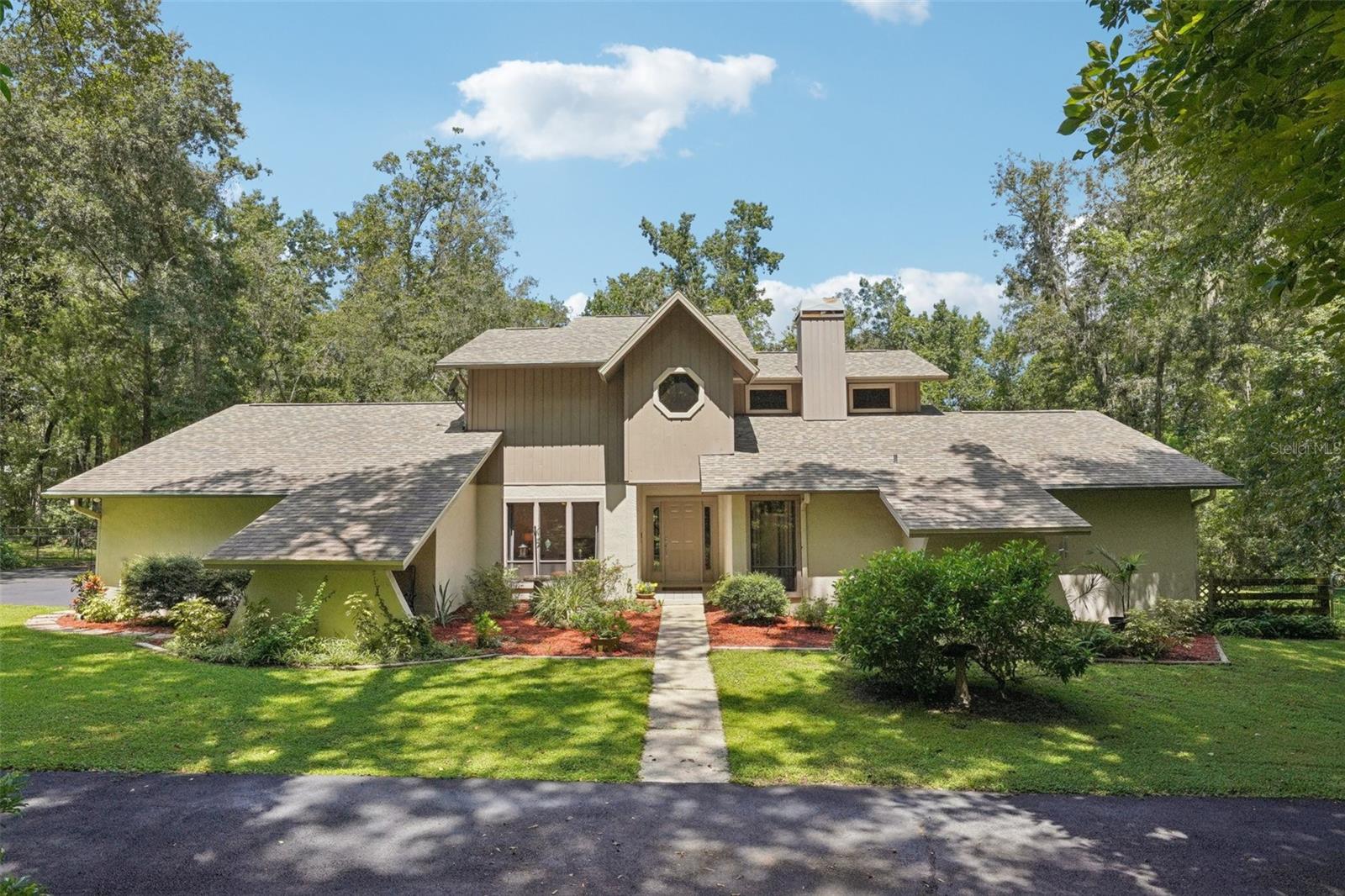 Secluded 2.50-Acre Retreat with Updated Home, Walking Trails & Scenic Views! Escape to your own private paradise with this beautifully renovated 3-bedroom, 2.5-bathroom home, perfectly situated on 2.50 acres of lush, wooded landscape. Surrounded by meticulously maintained grounds and private walking trails, this property offers unmatched peace, privacy, and connection to nature—yet is just minutes from modern conveniences. A circular driveway leads to a 3-car garage, welcoming you to a home designed for both comfort and function. Inside, the layout is warm and inviting. The primary suite is tucked upstairs for privacy and features a private deck overlooking the backyard, complete with treehouse-like views and a staircase down to the yard. The updated en-suite bath and large walk-in closet make this space a true retreat. Upstairs also includes a loft area, perfect for an office, study, or reading nook. Downstairs, two additional bedrooms sit across the hall from each other, offering convenience and comfort for family or guests. The private dining room is ideal for hosting gatherings, while the fully remodeled kitchen features gas appliances and modern finishes. Step outside to enjoy multiple outdoor living spaces, including a screened-in lanai with a relaxing patio, and an upper deck leading to the fenced backyard. Additional property highlights include 2-10x8 storage sheds, a 24x12 pole barn with electricity, and recent major updates: two new A/C units, new drain-field, new well pump, new decking, and a roof replaced just 5 years ago. Located just around the corner from Withlacoochee State Forest, you’ll have quick access to hiking, biking, and horseback riding trails, making this home a dream for outdoor enthusiasts. If you’ve been searching for a private, move-in-ready home with acreage and modern upgrades, this is the one—schedule your private showing today!