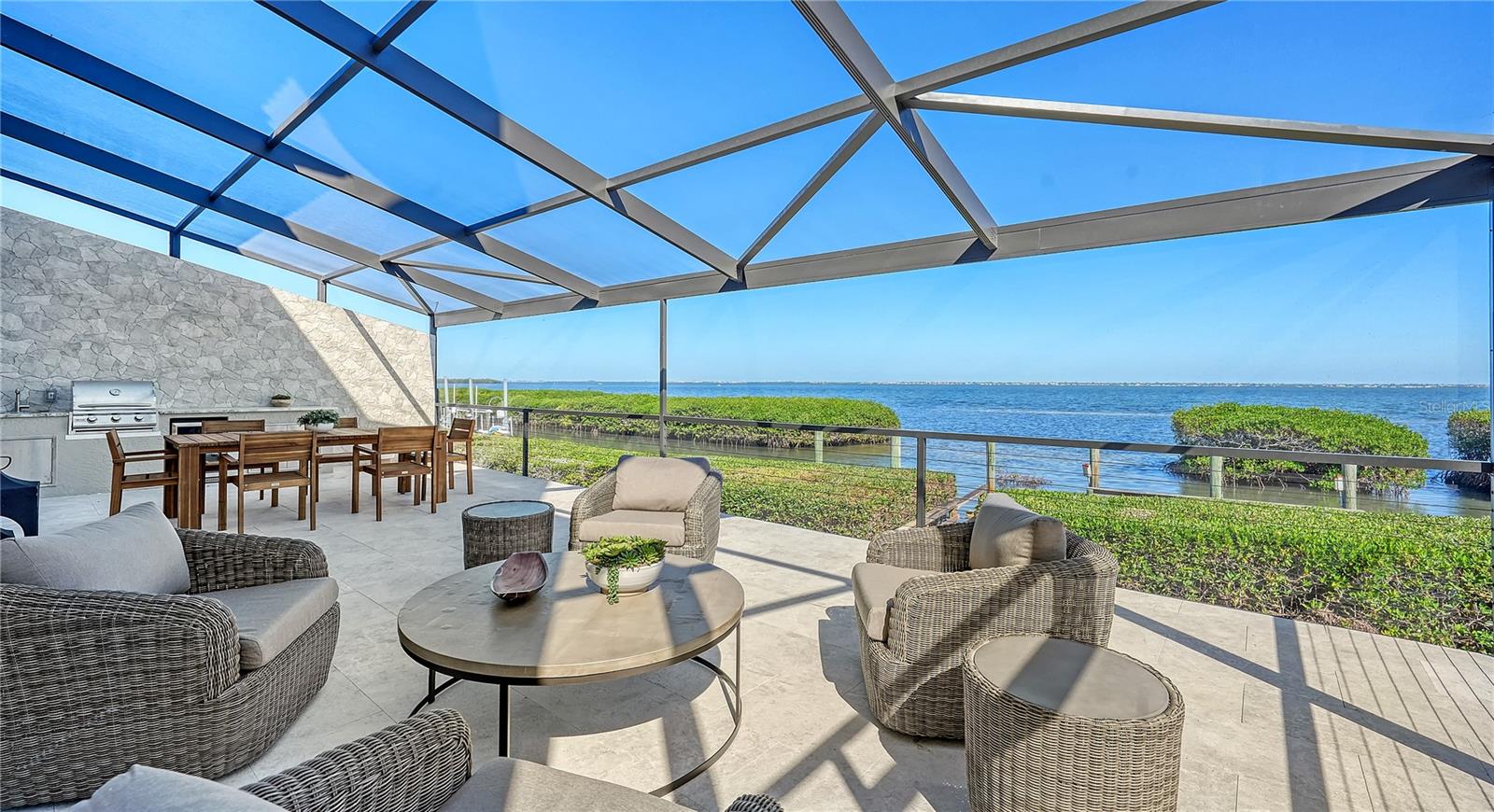 Move in today and embrace the ultimate coastal lifestyle in this completely updated, turnkey furnished bayfront residence in the highly sought-after Corey’s Landing neighborhood. Designed with a fresh coastal contemporary aesthetic, this four-bedroom home showcases meticulous updates, offering a sophisticated retreat located directly on Sarasota Bay. With its prominent waterfront location, cathedral ceilings, and walls of brand-new impact glass, the residence is bathed in natural light, framing breathtaking panoramic views from nearly every room. Every detail of this nearly 3,000-square-foot home has been thoughtfully curated, blending modern elegance with timeless comfort. Recent updates include a new roof (2019), freshly painted interior and exterior, oak hardwood flooring throughout, and updated electrical and plumbing. A brand-new dock and 10,000-pound boat lift, set for completion in 2025, provide direct access to the bay for boating enthusiasts. Custom lighting, tailored built-ins, and a water vapor fireplace set against a striking shiplap wall complete the picture of contemporary luxury. Step inside to an open and inviting floor plan, elevated by designer furnishings and modern finishes. Floating shelves, crown molding, and carefully selected details create a space that feels both chic and welcoming. The expansive great room flows effortlessly into the chef’s kitchen, a true showpiece. Custom natural wood cabinetry, quartz countertops with a waterfall-edge island, and a dramatic full-height backsplash are paired with premium Viking appliances, including a 6-burner gas stove and warming drawer. This gourmet space is as functional as it is stylish, offering plenty of room for cooking, dining, and entertaining. Walls of brand-new sliding glass doors connect the indoor and outdoor living areas. Outside, the screened lanai is a haven of relaxation, with Travertine tile decking, a summer kitchen with a built-in grill, and spacious lounge and dining areas. The serene primary suite, located on the main level, is a private escape with two walk-in closets and a beautifully renovated en-suite bathroom featuring quartz finishes and designer fixtures. Two additional bedrooms on the main floor, one currently used as a cozy den, provide flexibility for guests or a home office. Upstairs, the fourth bedroom suite and bonus room offer an ideal retreat for overnight visitors or a quiet sanctuary for relaxation. Corey’s Landing offers a maintenance-free lifestyle within the secure gates of Longboat Key’s exclusive Bay Isles community. Steps from your front door, enjoy the community’s tennis courts for a friendly match or head across the street to the heated pool and spa, perfect for unwinding or socializing with neighbors. Residents also enjoy private access to the Bay Isles Beach Club, where pristine Gulf beaches provide a serene escape just a bike ride or sunny walk away.