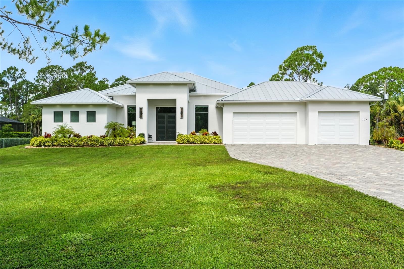 Welcome home! Offered FURNISHED and custom built in 2022, 709 15th St SW has it all! Strategically placed on 2.5 ACRES of FENCED-IN LAND, you’re sure to appreciate nature and privacy. As you step inside the double front door, you’ll notice the open floor plan — spanning nearly 3,500 sqft, 4 bedrooms (each with CUSTOM CLOSET SHELVING) + a den and 3.5 bathrooms are illuminated by natural light. All windows and doors are IMPACT RESISTANT, including the 90° sliders that provide unobstructed views of the screened-in lanai! The kitchen is light and bright, offering soft-close cabinets, quartz countertops, and stainless steel appliances. With an abundance of counter space, an induction cooktop, and a pot filler, cooking and hosting have never been easier. The primary bedroom is generously sized, with access to the pool, TWO CUSTOM CLOSETS, and a spa-like en suite featuring double vanities, a private water closet, an extra-large shower with double shower heads, and a soaking tub — all encompassed by gorgeous tile work. A split floor plan ensures you and your guests will appreciate the privacy, and 2 full guest bathrooms, including one en suite. The outdoor space is a retreat — offering a HEATED SALT WATER POOL/SPA, pool bath, and a CUSTOM OUTDOOR KITCHEN. With western exposure, you’ll never miss a Florida sunset! Other features of the home include EPOXY FLOORS in the 3-car garage, EV charging, an OVERSIZED LAUNDRY ROOM with a utility sink, TILE FLOORS THROUGHOUT, and beautiful TRAY CEILINGS in every room. Topped off with a METAL ROOF and located just minutes away from Naples’ finest dining, shopping, and entertainment options — the only thing missing is you. Schedule your private showing today!