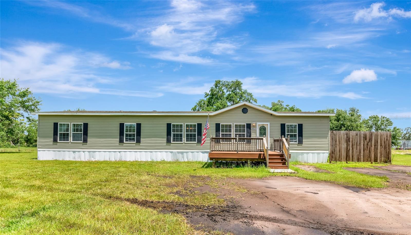 Discover this beautifully maintained and updated 4-bedroom, 2-bath manufactured home nestled on 5 high-and-dry upland acres, entirely outside of the flood zone, meaning no flood insurance required! This expansive property is fully fenced and ideal for those seeking space, privacy, and flexibility, bring your animals, toys, or even start your dream homestead. The home features a large open floor plan with generously sized bedrooms and living areas. A recently built wood deck graces both the front and rear entrances, perfect for enjoying peaceful morning coffee or entertaining in the evening. Inside, you’ll find a spacious kitchen with ample cabinetry, a dedicated dining area, and a large living room offering plenty of natural light. The split floor plan ensures privacy, with the primary suite offering a walk-in closet and en-suite bath. The land is level, dry, and completely usable with no wetlands, ideal for future structures, gardens, or simply enjoying wide-open space. With no HOA or deed restrictions, you’ll have the freedom to make this property your own. Whether you’re looking for a family retreat, a hobby farm, or simply more space to roam, this rare acreage opportunity offers the best of rural living with peace of mind, no flood insurance needed!