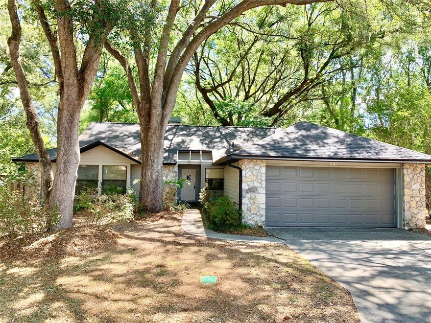 Beautiful welcoming home with no HOA! This wonderful home in the Fairfield neighborhood is nestled under a beautiful canopy of live oak trees. As you enter the home you fill find a large formal dinning room right off the foyer. The dinning room has 2 windows offering natural light for the space. The dinning room opens to the living room which features vaulted ceilings, a gorgeous stone fireplace, built in bookshelves and windows displaying the nature scape of the trees behind the home. The kitchen is spacious and features wood cabinets and stainless appliances. There is a pantry closet in the kitchen as well as breakfast area and laundry room.  When going down the hall toward the bedrooms you will find an entry closet and large linen closet. The two guest rooms are spacious and feature a window seat in each room. The primary bedroom is on the back of the home and has a high vaulted ceiling, large cedar lined walk in closet and ensuite bathroom. The primary bath has an updated vanity, updated lighting and huge tiled shower. The guest bathroom has also been updated with newer lighting, vanity and tiled tub/shower. From the living room you can use the double sliding doors to go out to the covered porch and deck area, great for entertaining or relaxing with a morning cup of coffee.  The home has a two car garage with newer garage door. Gas water heater was replaced in 2025 new rear fence and gate in 2025 and roof replaced in 2023. Short commute to Haile plantation for amenities and the weekend farmers market. Centrally located off 75th street(Tower Rd) and SW 8th Ave for an easy drive to the mall, HCA hospital, Haile Publix or down to Archer Rd and Tower Square. Great schools and great area to be! Come take a tour of this gem of a home.