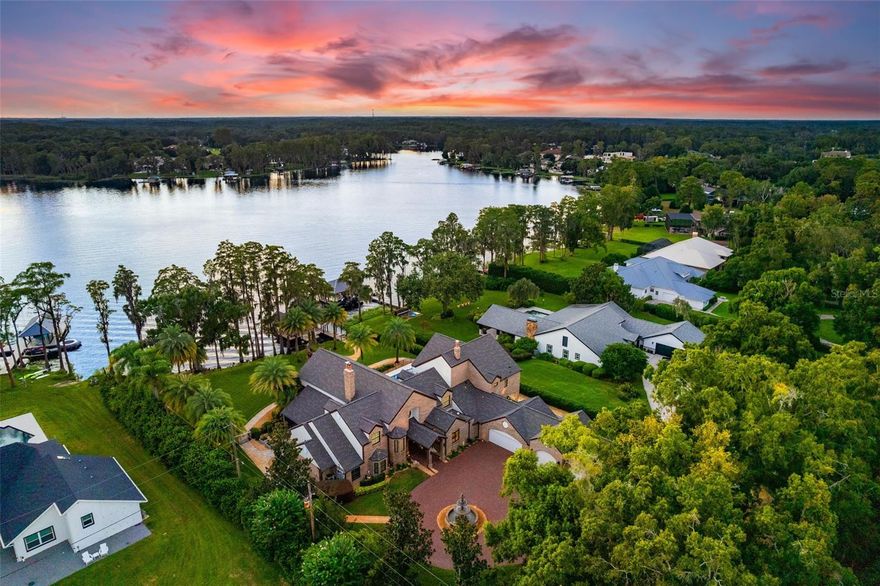 Prepare to be captivated by this once-in-a-lifetime opportunity to own a breathtaking 3-acre gated estate on Lake Keystone, Odessa's most desirable ski lake. One of only nine properties on the lake boasting 3+ acres and a west-facing view, this home offers a front-row seat to stunning sunsets every evening. As you enter through the private gate and down the winding driveway, you’re welcomed by immaculate landscaping illuminated by landscape lights, leading you to the grand entrance of this architectural masterpiece. The meticulously maintained grounds are secured with fencing and tall hedges for added privacy. The brick-clad, two-story estate exudes elegance. A circular driveway leads to a magnificent fountain and a five-car garage, air-conditioned by two mini-split systems—ideal for car enthusiasts or those seeking a year-round workspace. An exterior RV pad with a 50 AMP plug (2022) adds functionality to the exterior. Inside, you're greeted with panoramic views of Lake Keystone. The formal living room features a soaring 22-foot fireplace and pocket sliders opening onto the 1,127 sq. ft. screened lanai, blending indoor and outdoor living. The serene lanai features a koi pond (2023), outdoor kitchen with a new grill (2022), and seating areas to enjoy the lake views. The heart of the home is the kitchen, remodeled in 2024 with Taj Mahal quartzite countertops and freshly painted cabinetry. The adjoining bar area and island are perfect for hosting. This estate offers two owner suites. The first-floor suite, located off the formal living room, features a wood-burning fireplace and direct lanai access. The en-suite bath offers dual vanities, a soaking tub, walk-in shower, and two walk-in closets. Upstairs, the second owner's suite enjoys a private balcony overlooking the lake—a perfect spot for morning coffee or evening sunsets. This suite also offers two walk-in closets, a double vanity, and a walk-in shower. Upstairs features two additional guest bedrooms, each with its own en-suite full bathroom. A fifth bedroom downstairs serves as a versatile space, ideal for an office or additional guest room. The property has undergone $700,000+ in renovations, including a new heated saltwater pool and spa (2023) with a unique jet filtration system. Pocket sliders from the second living room lead directly to this outdoor oasis, complete with a new pool deck. The dock includes three boat slips. One is occupied by a pontoon boat and another by two jet skis with a remote-controlled cover. The dock is fully equipped with new electrical wiring, a speaker system, and its own Wi-Fi router, perfect for lakeside relaxation. The home is outfitted with state-of-the-art technology, including the Control4 Smart Home system for managing lighting, audio, security, and climate via phone. With 16 security cameras, hurricane impact windows, and a 36KW generator powered by four 200-gallon propane tanks, this estate is both secure and stunning. Thoughtfully curated and meticulously maintained, the home includes over 55 improvements, such as a new roof on the house, shed, and dock (2022), three new AC units (2022), and new electrical panels with surge protection. Rarely does an estate of this caliber, combining modern luxury, technological innovation, and natural beauty on a 3+ acre lot directly on Lake Keystone, become available. Make this unique waterfront haven yours, and experience life on Lake Keystone as it's meant to be. Not in a Flood Zone!