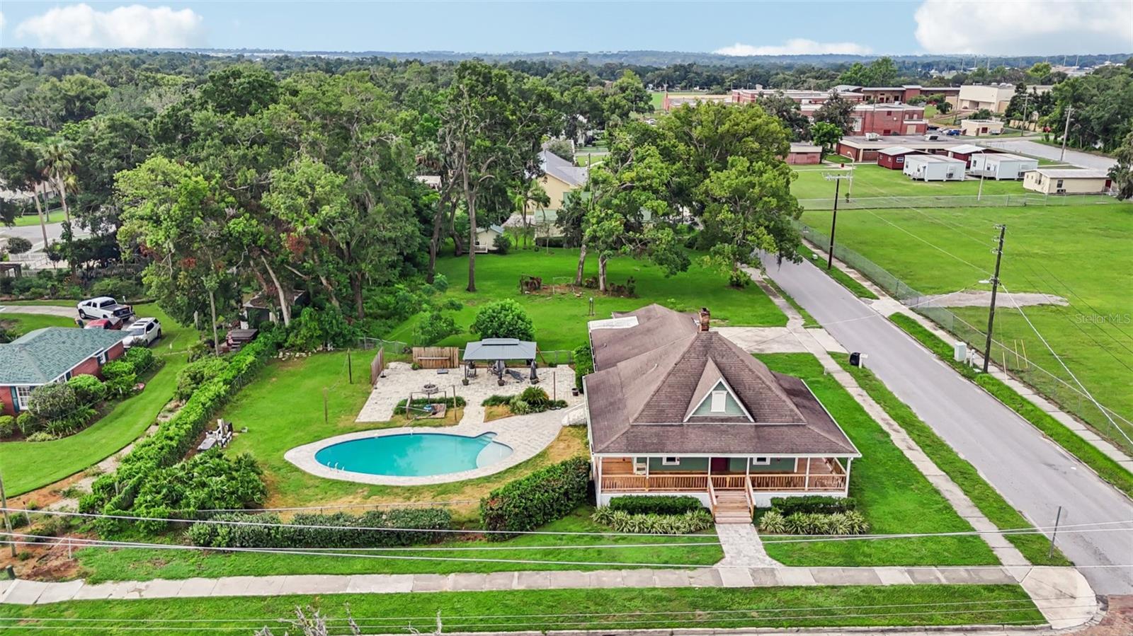 Step into a rare opportunity to own the John Raymond Homestead—an iconic piece of Dade City history originally built in 1887. This 3 bed, 3 bath, with an office 1,864 sq. ft. home masterfully blends timeless character with luxurious modern updates. Original hickory hardwood floors, interior walls, bathroom elements, built-in storage, and an oversized attic have all been thoughtfully preserved. Major renovations include a fully updated kitchen with quartz countertops, stainless steel appliances, updated bathrooms, new laminate flooring, brand-new windows, modern lighting, and fresh paint that pays homage to the home's historic roots. Soaring 10-foot ceilings enhance the main living areas. Additional recent upgrades include a new water heater and new gutters for enhanced efficiency and protection.
Enjoy the outdoors on the newly constructed wraparound porch or in your private backyard oasis featuring an inground pool with new pool pump, pergola, and firepit. Located just minutes—or a 5-minute bike ride—from charming Downtown Dade City’s boutique shops and dining. A vintage gem that’s fully move-in ready and truly unforgettable.