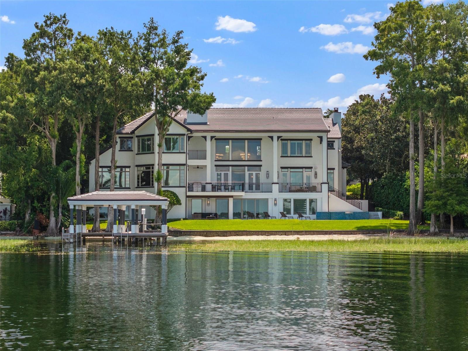 One or more photo(s) has been virtually staged. Introducing an exquisitely remodeled three-level Isleworth home on Lake Butler in the renowned Butler Chain of Lakes. Boasting a spacious 11,100 square feet of luxurious living space, this magnificent residence features 6 elegant bedrooms, 7 full bathrooms, and 3 convenient half bathrooms. Designed for both comfort and entertainment, the home includes an array of premium amenities such as wellness and recreation; featuring a relaxing sauna, gym, and golf simulator. An entertainment and leisure lounge includes a full bar, spacious theater room and access to exterior lounge area. The outdoor oasis is complete with a sparkling pool and hot tub, along with a fully refurbished dock with a brand-new boat lift. Luxury finishes such as detailed millwork and crown molding throughout; a grand soapstone fireplace and premium quartz and marble surfaces round out the estates’ style and classy décor.
This home is not only a haven of comfort but also offers convenience with an elevator and breathtaking lake views. Embrace the bright, open spaces and modern elegance. This stunning property is perfect for those who seek the finest in lakefront living.