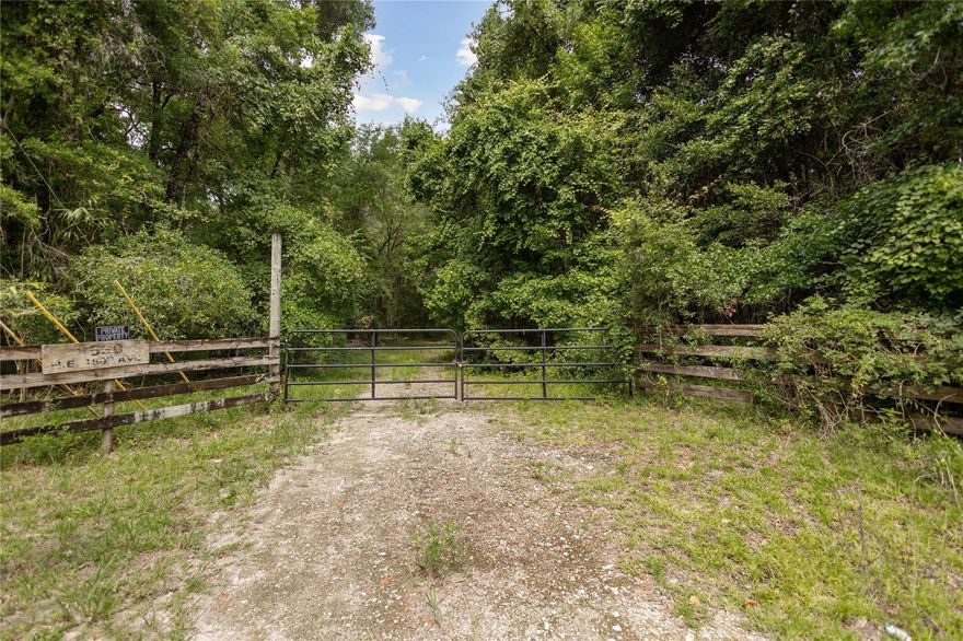 Experience the timeless beauty and peaceful charm of Old Florida on this exceptional 25.23-acre wooded estate, located within the private, gated Shell Pond Plantation community. Surrounded by gently rolling terrain, mature hardwoods, moss-draped oaks, and abundant natural beauty, this property offers the ideal blend of privacy, comfort, and rural elegance. Just minutes from the historic town of Williston—and approximately 30 minutes to Gainesville and 35 minutes to Ocala—this peaceful retreat is perfectly positioned for those seeking serenity without sacrificing convenience. A private, scenic drive winds through the property, revealing a thoughtfully developed homesite tucked away for maximum privacy. Improvements include a 24x40 metal RV carport fully equipped with power, water, and septic; a spacious 2,330 sq ft barn with an upstairs loft; a fully finished downstairs area featuring a bathroom and washer/dryer; and a charming 28x11 tiny home ideal for guests, weekend stays, or short-term rentals. The property also includes two wells, providing reliable water access for residential or agricultural use. The electric gated entry to the community enhances security and exclusivity, while the horse-friendly environment makes it ideal for equestrian living, with ample space for paddocks, riding, or future expansion. The property is teeming with wildlife, including white-tailed deer, Osceola turkey, and other native Florida species—making it a true haven for nature lovers, hunters, or anyone seeking a connection to the outdoors. Whether you’re looking to build a custom estate, develop a private equestrian facility, or simply escape to the tranquility of the countryside, this property offers endless potential and modern comforts in a truly picturesque setting. Please note: the driveway leading to the property is not included in the parcel’s acreage.