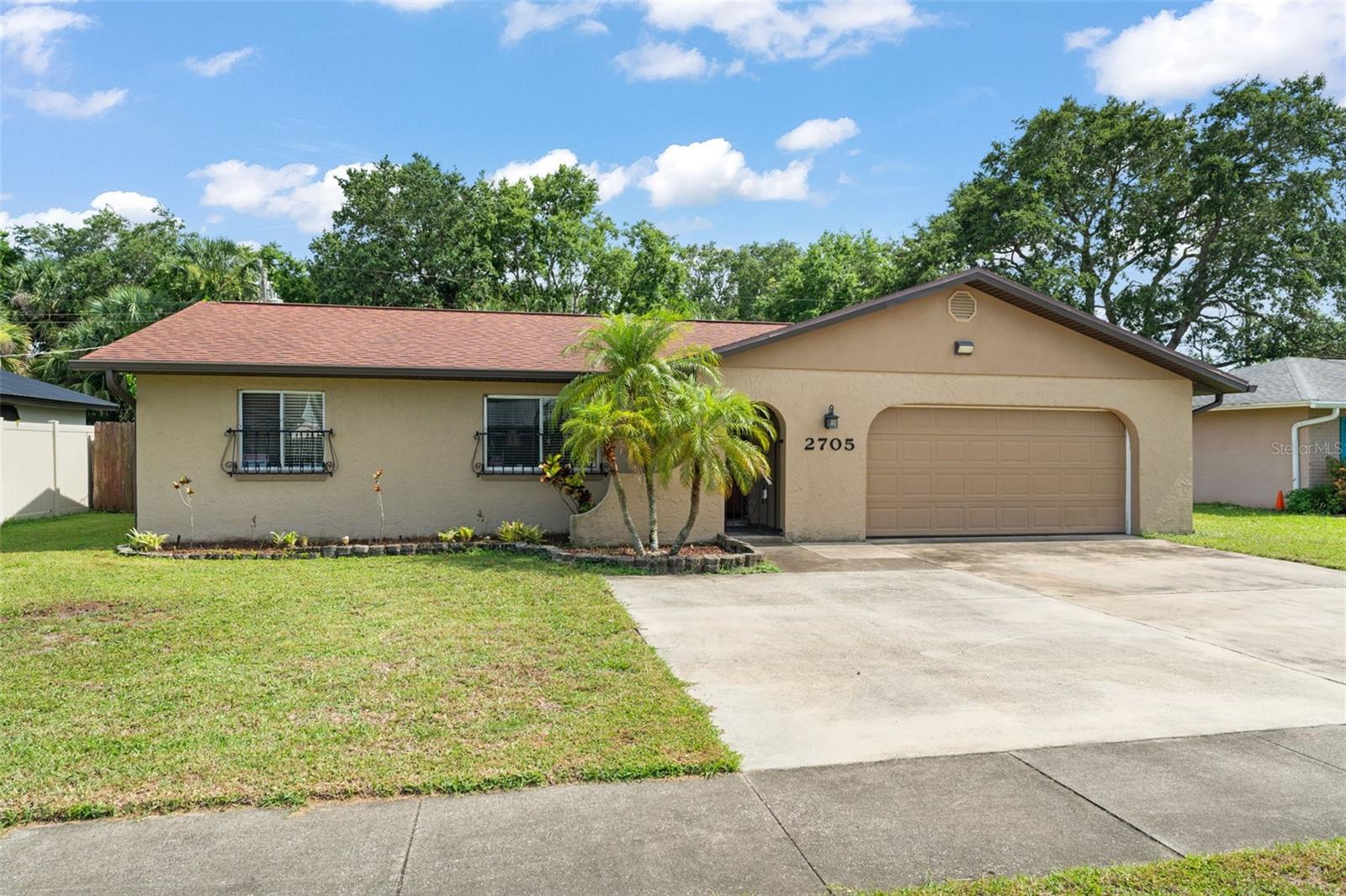 **This property qualifies for a closing cost credit up to $5,600 through the Seller’s preferred lender.** This beautifully maintained home comes FULLY FURNISHED, making your move-in seamless and stress-free. Nestled in the heart of Titusville, this charming 4-bedroom, 2-bathroom single-family home is full of warmth, functionality, and the kind of thoughtful touches that make a house feel like home. With a 2-car garage and an extra-wide driveway, there’s plenty of room for guests, hobbies, and everyday ease. Step inside and be greeted by the light-filled living room, where tile flooring and a front-facing window create a welcoming atmosphere. Just off the living room, the primary suite offers a quiet retreat with parquet flooring, an elegant arched passthrough, a walk-in closet, and a private en suite bath—complete with direct access to the backyard, perfect for morning coffee or quiet evenings under the stars. The thoughtful split-bedroom layout ensures privacy, with additional bedrooms and a full bathroom tucked just off the dining area. Down the foyer, you’ll find a convenient coat closet and access to the spacious garage. The heart of the home lies in the open kitchen and dining area. Bright and functional, the kitchen features white cabinetry, stainless steel appliances, and a breakfast bar—ideal for casual meals or entertaining. The dining area, complete with a charming chandelier, offers ample space for sit-down meals, and the current owners have even created a cozy bar space for additional seating. From the dining room, sliding glass doors lead to a screened-in patio that’s perfect for relaxing or entertaining year-round. Beyond that, a fully fenced backyard awaits—a blank canvas ready for your personal touch. There’s even a 12' x 26' composite deck beside the outdoor building, providing extra space for outdoor living or storage. The outdoor building measures 12' x 16', offering ample room for tools, hobbies, or whatever suits your needs. These measurements help give a better sense of scale than the pictures alone. Additionally, there is a chain-link fence behind the privacy fence, adding an extra layer of enclosure. Whether you’re looking for room to grow, space to gather, or simply a place to call your own, 2705 Wilmette Ave is ready to welcome you home—furniture and all.