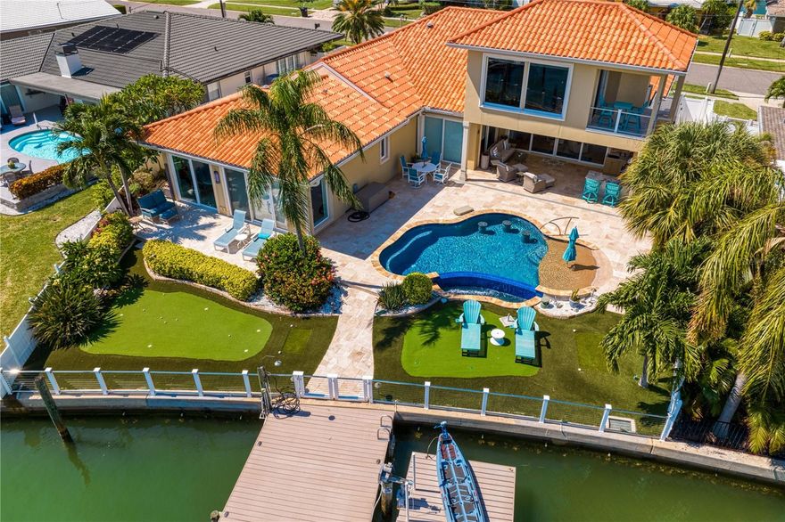 A Waterfront Tropical Paradise in Island Estates! Totally renovated home with high quality finishes. First floor Master Suite with stunning water views including newly remodeled master bath a massive 10X12 closet, Guest bedroom En-suite with full bath, and 3rd bedroom currently used as a 11X19 office with a wet bar/ coffee bar with a sink, dishwasher and refrigerator.  The new design includes upgrades and custom touches ranging from crown molding, handcrafted cabinetry, Hunter Douglas remote blinds and hickory floors that enhance and elevate the interior’s gourmet kitchen, casual dining area and large living room. The well-quipped kitchen includes two dishwashers, three ovens, two sinks, top-of-the-line appliances, kitchen counter and island seating plus adjoining large pantry and laundry rooms with loads of storage space. Open concept living combining kitchen, dining room and living room with water views throughout. Magnificent second floor 4th bedroom with outstanding water views that currently serves as a gym/ fitness center and has a murphy bed with full bath and has a separate entrance by outside staircase so this can serve as an In-law suite!  Multi Room sound system with speakers in nearly every room and outside. State of the art security system with smart screen technology and 8 security cameras. Built-in Yeti Cooler at pool for convenience.  Engineered Hardwood in Master Bedroom.  All Amish custom-made cabinets.  Deep, wide open canal with boat dock, recently updated outdoor kitchen with top-of-the-line Twin Eagle appliances. Heated saltwater pool, Awning, and privacy fence on second outdoor deck off master suite. Large country club like putting green in the backyard off the pool area.  Large air conditioned “stand up” attic for storage with versa lift to move items up and down.  10 ft ceilings throughout house, Generac “whole home” Generator. Top of the line and newer Trane AC units.  All TV mounts will stay. The private dock and kayak lift protected by canal waters while directly accessible to fishing, boating and sailing excursions along the Gulf of Mexico. Central Vac. SEE attachment for all highlights in the home.  SELLER WILL LEAVE ALL ELECTRONICS AND ALL OUTDOOR AND INDOOR FURNITURE FOR THE BUYERS CONVENIENCE.