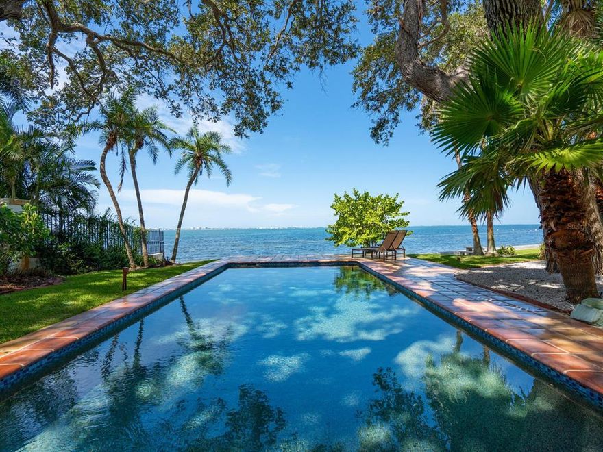 This enviable address, with private frontage on Sarasota Bay, showcases spectacular water and sunset views. The hurricane shutter protected home resides on a beautifully landscaped lot. Concrete garden walls surround the property and a stately customer electric gate system ensure serenity and security. Lush trees and beautifully manicured gardens create a personal oasis around the home. The blend of classic and modern architecture with traditional features but an open layout lends to the home’s spacious feel and coveted access to the Sarasota Bay waterfront. Open sightlines throughout the interior showcase the bayfront location and access to the gardens and pool. The enormous owner’s suite occupies the second level, with stunning water views through oversized sliders that open to a large private balcony. On either side of the suite, there are two full baths, each with extra-long vanities and generous walk-in closets. Mezzanine space on the second floor now used as a private lounge and a custom art installation above the bed add luxury to the sprawling suite. On the entry level, the foyer opens to a large great room with picture windows and large sliders that extend the living space to the waterfront terrace. A spacious dining area, also facing the water, features additional sliders to the exterior, with open flow to the great room, distinctive chandelier lighting and ample seating room for 10 or more. The dining room is adjacent to the kitchen, laid out perfectly to maximize function and flow, with massive counterspace including a central island, sleek modern cabinetry and minimalist recessed lights. Top-line appliances include newly installed Dacor dishwasher and microwave, wall oven, six-burner gas stove and side-by-side Sub-Zero refrigerator. Beyond the foyer, a private alcove leads to two first-floor bedrooms and a guest bath. The first bedroom features ample built-in storage and the second bedroom, currently configured as an office, has an en suite full bath and large picture windows showcasing the bay view. Additional features include a waterfront sitting area adjacent to the central great room, water filtration, new pool equipment (2021), and mission-style terracotta tile and wood floors complementing the Mediterranean home style. Indian Beach/Sapphire Shores is one of Sarasota’s most scenic neighborhoods, with an established tropical landscape and iconic homes. This location offers easy access to downtown amenities, Ringling Museum, the airport, and shopping and dining for lifestyle convenience without noise and distraction. Bay Shore Road is lined with stunning multimillion-dollar estates, complementing the value of this home. Room Feature: Linen Closet In Bath (Primary Bedroom).