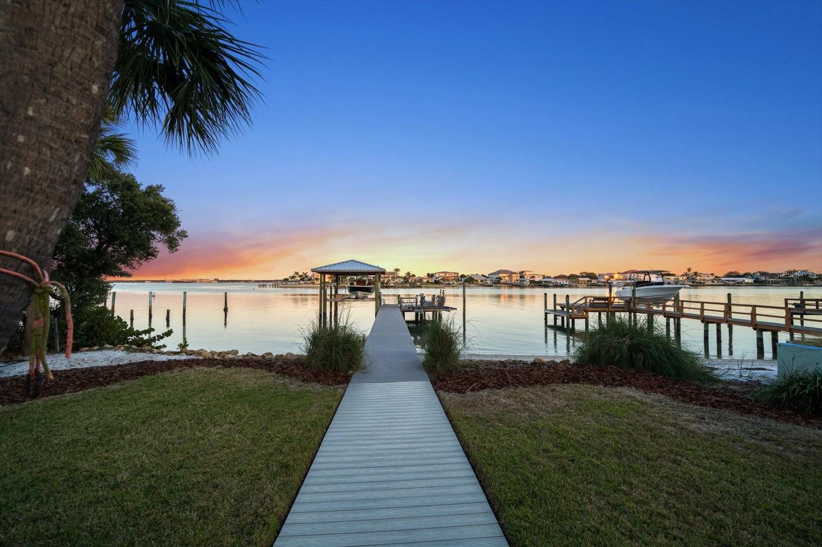 Welcome to the epitome of coastal living in this meticulously renovated 1930s beach house, a true gem nestled on the coveted shores of Clearwater Beach. The undeniable curb appeal, adorned with lush tropical landscaping and a distinctive metal roof, sets the stage for an inviting retreat by the sea.
As you step through the front porch, the breathtaking panoramic views of the Intracoastal unfold, creating a picturesque backdrop for your coastal lifestyle. The kitchen, bathed in natural light, becomes a culinary haven with its granite counters, stainless steel appliances, and charming beadboard vaulted ceilings echoing the rhythmic melody of the waves just outside.
The dining room seamlessly connects to the kitchen, featuring a cozy fireplace and an arched entry to the sunroom, where walls of windows invite the outdoors in. Custom cabinetry in the living room provides the perfect display space for seashells and also contains a queen size Murphy bed + additional storage. Step through the french doors onto the expansive deck leading to your private beach and boat dock. The primary bedroom, with its vaulted ceilings, offers a serene escape bathed in abundant natural light and showcasing stunning sunrises from the comfort of your king size bed. The ensuite bath, adorned with a beadboard vanity and walk-in shower, adds a touch of luxury to your daily retreat.
Downstairs, additional bedrooms, large enough for queen size beds, are bathed in light, boasting ample closet space and sharing a spacious hall bath. A generously-sized laundry room adds convenience to your beachside lifestyle. Outside, the expansive TREX deck becomes an inviting space for entertaining amidst breathtaking vistas, where the playful presence of dolphins and manatees adds a magical touch to your coastal experience. The large attic provides ample additional storage space.
This exclusive property, one of only six with a private sandy beach, allows for seamless water activities such as kayak and paddleboard launching, offering an ideal spot for a refreshing swim. The TREX dock and covered 50K pound boat lift cater to the desires of water enthusiasts, completing the allure of this waterfront haven. Hurricane impact rated windows through out provide added protection, ensuring peace of mind.
Enjoy the convenience of walkability to Clearwater Beach, and take a short stroll to discover local restaurants and shopping delights. This beach retreat harmoniously blends modern amenities with timeless charm, presenting an unparalleled opportunity to live the quintessential beachfront lifestyle in Clearwater. Welcome home to your coastal paradise!
