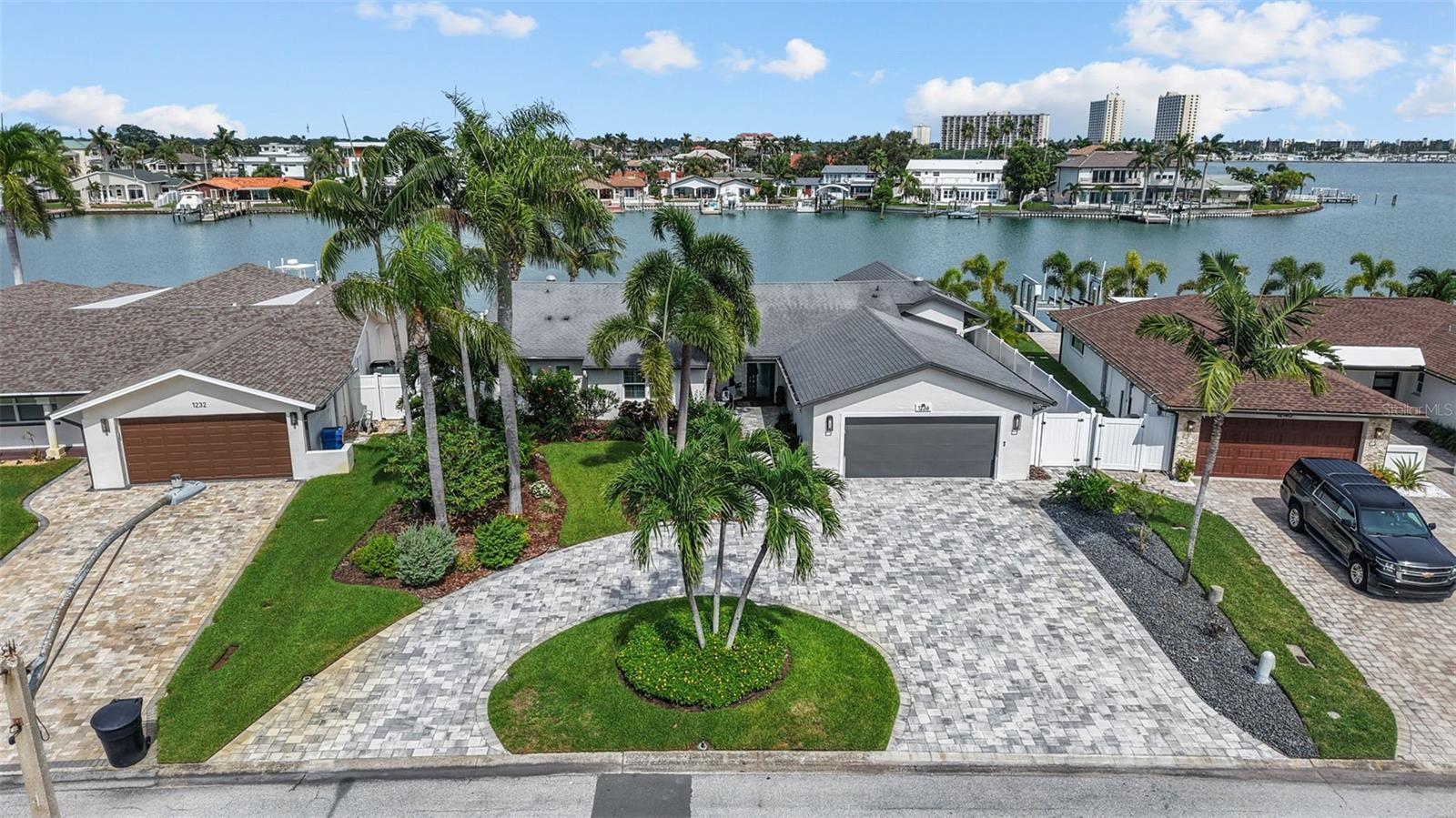 LIVE ABOVE IT ALL – ELEVATED WATERFRONT LUXURY! This 4 bedroom 3.5 bath home with EXTENSIVE HIGH-END UPGRADES sits on a HIGH LOT WITH NO FLOOD WATER INTRUSION TO THE HOME OR GARAGE (updates completed prior to Hurricane Helene). Walls of hurricane impact glass frame sweeping open Intracoastal views beneath soaring cathedral ceilings, with new hurricane shutters adding storm protection and helping keep the home cool while you travel. The chef’s kitchen offers Wolf and Bosch appliances, quartzite counters, wine storage, hidden walk-in pantry, and natural gas cooking. Dual waterfront suites include spa baths, custom closets, and direct access to the saltwater pool and spa. Updates feature a new high seawall, HVAC, tankless water heater with recirculating pump, reverse osmosis system, plumbing upgrades, full-house generator, newly paved driveway, and natural gas service. Outdoor living includes a summer kitchen, fire pit, rain-curtain pool entry, lush landscaping, and composite dock. This DEEP WATER LOT PROVIDES 83 FEET ON THE WATER WITH A 13,000 LB BOAT LIFT, KAYAK AND PADDLEBOARD LAUNCH, AND PLENTY OF SPACE FOR ADDITIONAL WATERFRONT TOYS. Situated in one of the most coveted waterfront communities in Pinellas County, just one mile from the beach, restaurants, entertainment and more. You will feel right at home in this friendly community of Yacht Club Estates.