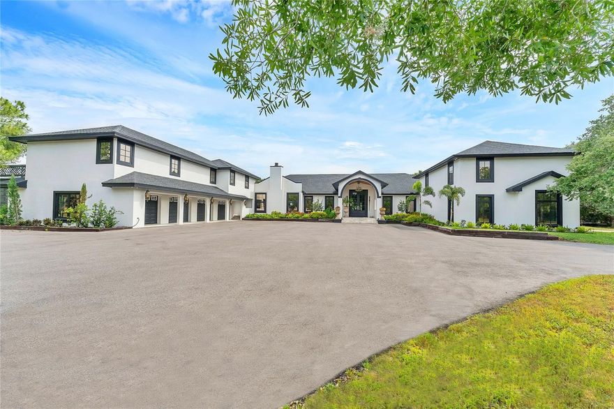 You must see the film. A masterclass in boldness and individuality, this 8,460-square-foot ranch was artistically conceived by award-winning firm, JKL Design of Sarasota. Every area of the residence has been re-imagined, inside and out. The list of improvements and upgrades is extensive. An extended paved driveway rolls through the 10-plus-acre estate to the stunning façade of this six-bedroom, 5.5-bath showstopper. It’s a welcome approach. Carefully curated with architectural matte black windows, grand 10-foot double entryway doors and ornate outdoor carriage lamps, the residence exudes stateliness and charm. On the interior, the open concept floor plan is graced with elegant European blonde oak flooring and uncommonly smooth level 5 drywall. Sophistication is imbued in the daring and fanciful wall colors and surface treatments. The great room is centrally located, effortlessly connecting the kitchen, lounging, billiards, gaming and entertainment areas, all in a thoughtful and inviting way.  Oversized cantilever sconces anchored to a kitchen wall, clad with vintage Americana signage, suspend above the sleek, matte black island countertop, which houses an abundance of storage on two sides. Floating shelves and custom kitchen cabinetry, made of reclaimed wood, were fabricated onsite in the home’s garage workshop. Soaring vaulted ceilings and a bank of windows encase an intimate dining nook that provides table seating for six. Cleverly, a separate working kitchen and scullery reside behind the main kitchen and contains a meal prep station, an abundance of cabinet storage, sink, refrigerator, wall ovens and a gallantly designed cocktail station. The views from here overlook the oversized, heated saltwater pool and spa with white marble sundecks. Each of the two imaginatively styled first-floor primary bedroom suites is drenched in natural light with direct access to the pool and spa. The clawfoot cast iron freestanding tubs are center stage in each dramatic primary bath. Large format tiles and mosaic inlays add sophistication to the oversized showers. Custom walk-in closets provide luxury design elements including stamped leather chests, iron shelving with lighting, custom slide drawers and crafted built-ins. The first floor also boasts a dedicated office for focused work, while the music lounge, complete with baby grand piano, echoes the home’s appreciation for art and culture. The family room, warmed by a modern wood-burning fireplace, offers a cozy retreat. Organized into two wings from the main house, the east wing boasts a four-car garage and a second level loft apartment containing two guest bedroom suites, a movie and gaming area, and kitchenette. The west wing offers a two-car garage and workshop and above it, two additional guest bedrooms, a great room and full bath. Set against a backdrop of serene countryside less than 10 minutes from the highway, and 20 minutes to downtown, this estate offers a rare embodiment of luxurious privacy and accessibility to all Sarasota has to offer. For those who seek a sanctuary and a statement, this estate is an invitation to live boldly, thoughtfully and without compromise. Plan a visit to one of the most celebrated ranches in Sarasota. You’ll be excited you did.
