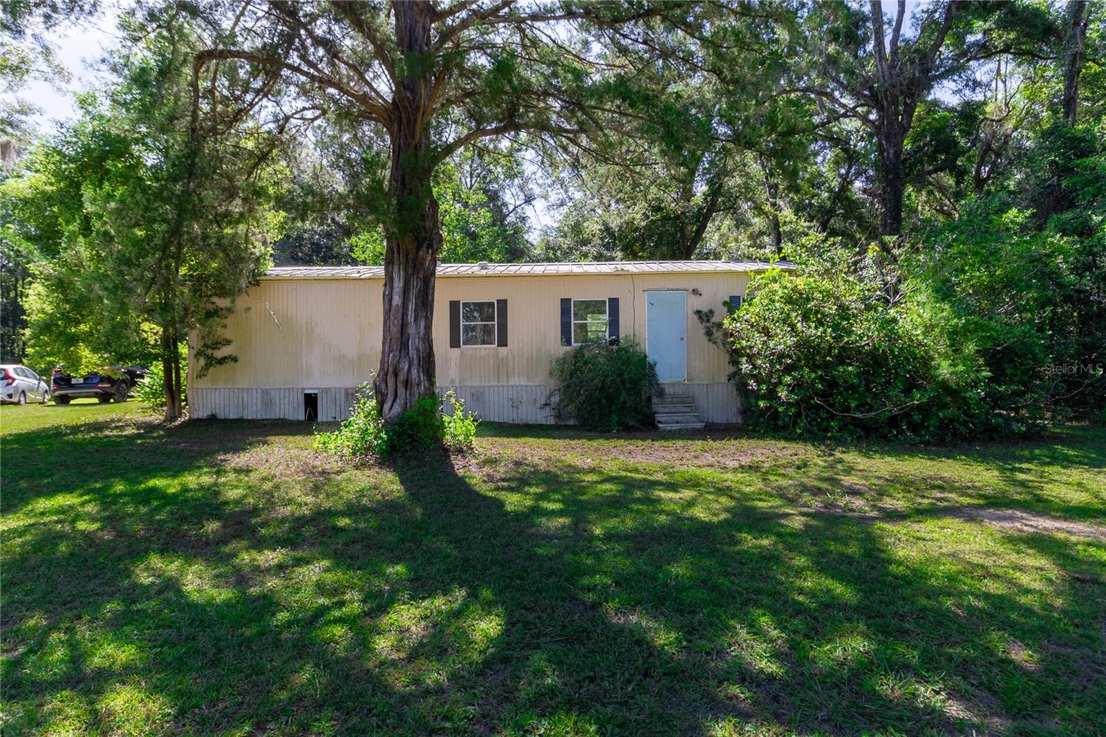Tucked away just 4.5 miles from the new Newberry Publix, this enchanting 5.27-acre property is a hidden gem waiting to be discovered. A beautiful mix of cleared land and natural woodland, the property is adorned with mature live oaks, longleaf pines, cedars, Persian silk trees, American beautyberry, and more—offering both privacy and character that only time can create.
At the front of the property sits a 2-bedroom, 1.5-bath “handyman special” with 644 sq. ft. of cozy living space. Enjoy quiet mornings on the screened porch or take in breathtaking southeastern sunrises from the spacious deck. Though modest, the home offers solid potential—with a 4-year-old metal roof, a 9-year-young well, and a septic system that’s clear and ready for use.
Additional features include a fenced dog run, two storage sheds, and ample space for outdoor living. Whether you’re looking to renovate the current home, build your dream estate, or create a private weekend retreat, this Agricultural zoned and no flood zone property is a blank canvas in a prime location—just off NW CR 235 with easy access to both Alachua and Newberry.
Bring your animals, your outdoor toys, and your imagination. Photos can’t capture the peace and beauty of this land—you truly have to see it to believe it.