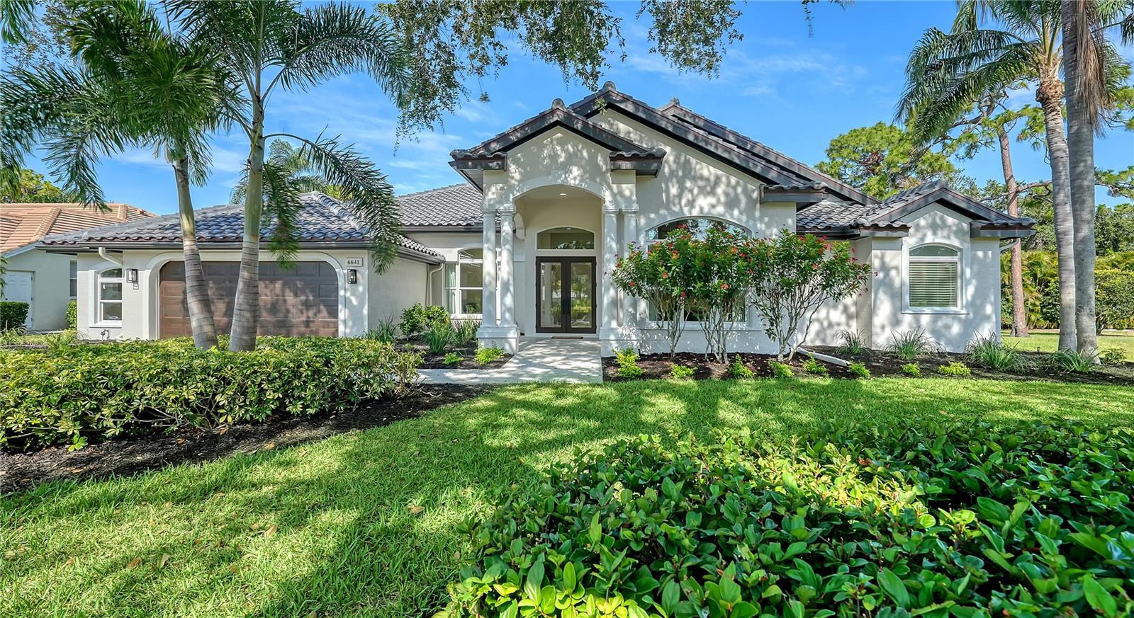Welcome to a sophisticated blend of luxury and leisure in the exclusive enclave of Saint James Crossing, nestled within the gates of University Park Country Club. This meticulously updated four-bedroom pool home offers over 3,000 square feet of refined living space designed for effortless entertaining and serene daily living. From the moment you step through the double glass doors, you’re greeted by a sun-drenched open layout that flows seamlessly beneath soaring vaulted ceilings adorned with custom wood beams. This home has been beautifully reimagined in 2025 with a brand-new roof, windows, and sliding glass doors, as well as upgrades to the electrical and designer interior. Wide-plank hardwood flooring extends throughout the main living areas, grounding the modern design with warmth and character. At the heart of the home, a chef’s kitchen dazzles with crisp quartz countertops, custom cabinetry, designer lighting, and a spacious island with seating for four – perfect for family gatherings. The adjacent family room exudes a relaxed sophistication with a feature wall showcasing a linear fireplace and built-ins, while full walls of glass overlook the screened lanai and sparkling pool beyond. Retreat to the tranquil primary suite, where private patio access, a sitting area, and large walk-in closets elevate comfort. The spa-like bath invites indulgence with a freestanding soaking tub, dual vanities, and an oversized rainfall shower wrapped in luxurious tilework. Two additional guest bedrooms—each with high ceilings and ample natural light—provide versatility for family, guests, and a dedicated home office (fourth bedroom). Step outside to enjoy year-round Florida living in your own tropical sanctuary. The expansive screened lanai with paver decking, covered lounge space, and a pristine pool bordered by lush landscaping offers the ideal backdrop for quiet mornings or sunset swims. Set within one of Sarasota’s most prestigious master-planned communities, Saint James Crossing provides residents with access to an award-winning lifestyle. Enjoy 27 holes of championship golf, 11 Har-Tru tennis courts, four pickleball courts, a croquet lawn, fitness center, and a vibrant social calendar—all secured by a staffed gatehouse and framed by shaded, walkable streets. New homeowners are required to purchase a membership, ensuring a thriving, well-maintained community for years to come. Beyond the gates, you’re minutes from the upscale shops and dining of University Town Center, cultural experiences in downtown Sarasota, and the soft sands of Siesta Key and Lido Beach. Whether you're looking for a full-time residence or a winter retreat, this turnkey home offers the perfect harmony of style, comfort, and community.