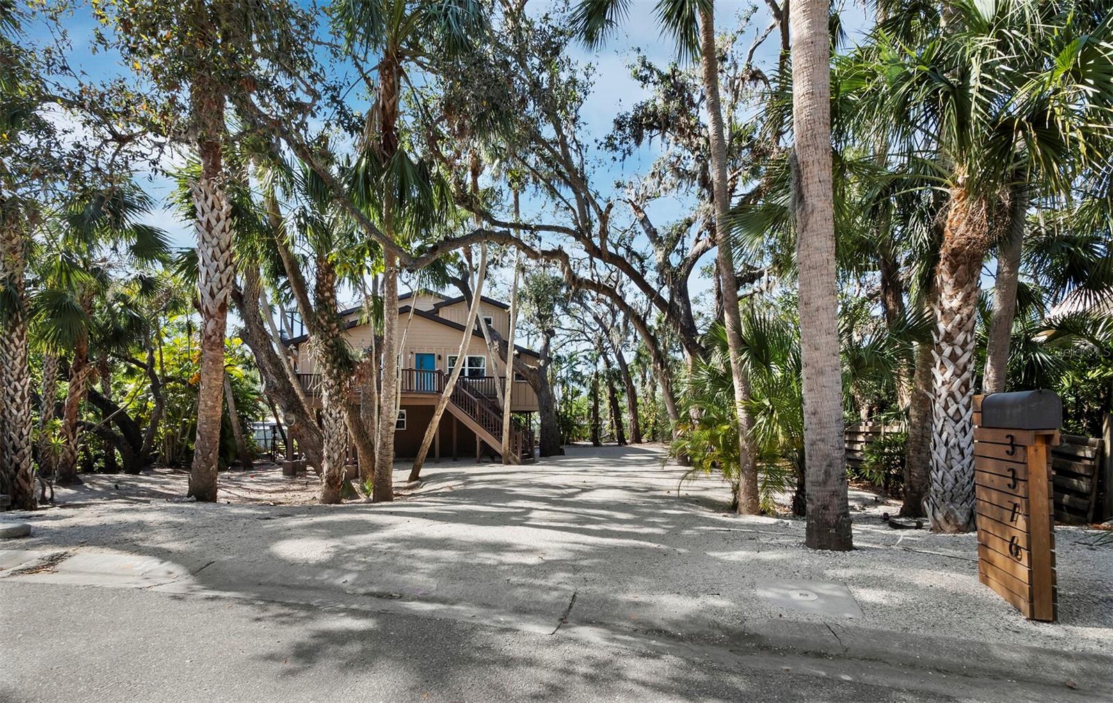 One or more photo(s) has been virtually staged. Located in popular and convenient South Gate, this home is anything but typical! Elevated and surrounded by gorgeous nature, it has the feel of a luxurious tropical treehouse. From the large lot on a quiet & private street to the huge deck at the front door, you will appreciate the cool style as soon as you pull up…this property is unique and beautiful and nestled into its surroundings in a way that you don’t often see. Phillippi Creek winds around the edge of the lot and you’ll often spot egrets, wood storks, blue heron, and even roseate spoonbills wading there, plus bald eagles and owls are known to nest nearby – it is truly a nature-lover’s paradise! Also, the creek is ideal for kayaking and you can launch right from the property and paddle all the way to in intercoastal if you like. The first floor features a spacious 2-car garage and loads of storage, with all living space located safely high above on the second and third stories. Soaring ceilings and a beautifully updated & chic kitchen define the main living area, with an elegant bath and the two nicely-sized bedrooms located on the same level. The property is offered furnished for your ultimate ease and convenience. You’ll adore the large screened deck with grill & gas fire pit too! Tucked into the treetops, this outdoor living space is infinitely enjoyable. Ascend to the main bedroom suite, where you will be absolutely wowed by the spaciousness and fantastic high ceilings! There is plenty of room for a sitting area, desk, or even a yoga or meditation spot so you can create a true retreat. The updated bath features a freestanding tub and shower with space for two, and the large walk-in closet has ample space and is already customized! The laundry is conveniently located upstairs in a second closet, and there is also a second fabulous screen porch to enjoy. Many smart home features make for easy living: Lutron lighting throughout, in-ceiling speakers, Arlo camera system, and an August automated front door lock. This entire home is perfectly updated and ready to enjoy and you will also be thrilled with the location: easily drive or bike to Siesta Key Beach or downtown, or hop on the nearby Legacy Trail! 10 minutes or less will get you most places, which is a rarity in Sarasota. Your tropical paradise treehouse awaits…come take a look at this unique and dazzling property today!