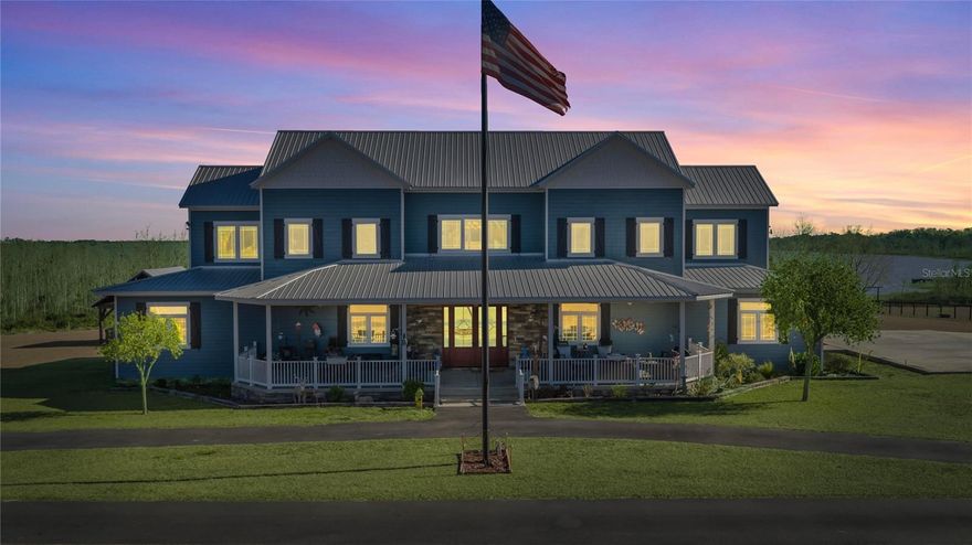 Experience extraordinary lakefront living in this breathtaking waterfront farmhouse estate set on 8.71 acres beneath a canopy of mature oaks. Offering over 5,500 square feet in the main residence plus a detached two-story guest apartment, this private compound blends upscale design, resort-style amenities, and wide-open acreage—perfect for multi-generational living and entertaining.The striking exterior showcases a classic metal roof, crisp coastal-inspired façade, and deep wraparound porches with panoramic water views. Inside, soaring ceilings, wood-look tile flooring, and sun-filled spaces create an inviting yet dramatic atmosphere. The great room opens seamlessly to the chef’s kitchen featuring custom cabinetry, granite countertops, a large center island with farmhouse sink, gas cooktop, double ovens, bar seating, and a massive walk-in pantry. Oversized dining windows frame picturesque lake views.The main home offers four bedrooms and four and half baths, including two owner’s suites. The primary suite on the main level overlooks the lake and features a spa-inspired bath with clawfoot soaking tub, dual rain showers, double vanities, and an expansive walk-in closet. A private office with French doors and built-ins, a dedicated movie room, and an oversized laundry room with Murphy bed, utility sink, and abundant storage enhance everyday functionality.Upstairs, a loft overlooks the main living area and entryway, flanked by two bedrooms—one with an oversized bath and walk-in closet, and another with a private bath and adjoining game room.Outdoor living is exceptional with a lakeside pavilion offering a hot tub, outdoor kitchen, with butcher block counter tops, gas grill, wood-burning fireplace, and TV. Enjoy your private sandy beach and dock with gazebo—ideal for boating, fishing, or sunset relaxation.Equestrian amenities include a two-stall barn with wash rack, feed and hay storage building, two-stall lean-to, round pen, and expansive fenced pasture. Car enthusiasts will love the five-bay garage with a two-bedroom, 1.5-bath apartment, plus an additional three-bay garage providing incredible storage and flexibility.A rare opportunity to own a secluded lakefront retreat that seamlessly combines luxury living, equestrian facilities, resort-style outdoor spaces, and wide-open acreage.