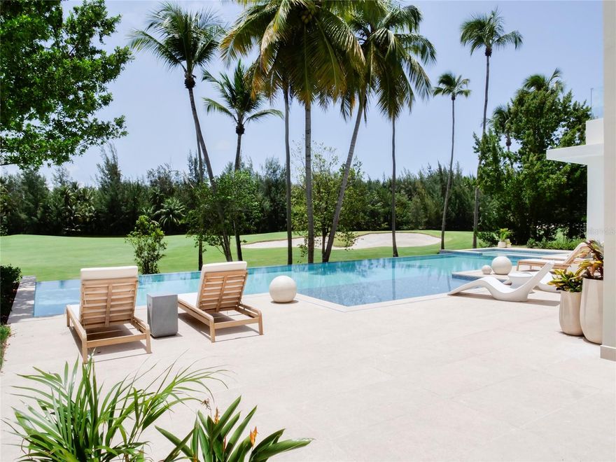 Impeccably crafted and exceptionally spacious, this elite residence at Four Seasons Resort
Puerto Rico at Bahia Beach offers over 15,000 square feet of refined living across three finished
levels, set on nearly half an acre with sweeping views of a tranquil lake and championship golf
course.
Designed to harmonize with its lush surroundings, the home showcases professionally curated
interiors that frame panoramic vistas in every direction—serene golf course and lake views to
the south, the verdant peaks of El Yunque National Forest to the east, and effortless access just
steps away to the resort’s pristine two-mile crescent beach.
At the heart of the home, a bespoke Italian kitchen blends striking design with everyday
functionality, anchored by a dramatic waterfall island and appointed with premium Thermador
appliances, an expansive wet bar, wine refrigeration, and a discreetly concealed pantry for
seamless entertaining. The open-concept layout transitions effortlessly to the outdoor living
spaces, where the estate transforms into a private resort ~ 7000 SQFT of outdoor finished
space —featuring a 55-foot infinity pool with bench seating, waterfall feature, a 12-person
heated hottub, sun shelf with bubblers, outdoor showers, a dedicated pool bath, and a fully
equipped designer BBQ pavilion with bar seating. Dual-level terraces, connected by elegant
glass-railed stairways, provide multiple settings for entertaining and relaxation, all appointed
with sophisticated furnishings.
The residence offers six generously proportioned bedroom suites, each with a private, elegantly
appointed bath and expansive custom Italian walk-in closets. The primary suite is a true
sanctuary, capturing breathtaking views from every angle and complemented by a spacious
sitting area, a spa-inspired bath with dual showers and soaking tub, and a couture-style
dressing room with center island and bespoke cabinetry.
An upper-level lounge with wet bar opens to a secondary terrace overlooking the pool and
fairways, while the rooftop terrace delivers extraordinary 360-degree views encompassing the
ocean, rainforest, and surrounding landscape—ideal for sunset entertaining.
Finishes throughout include oversized European 4’ x 4’ travertine-style tile, the special splash of
modern wall decorative textures, complemented by two additional powder rooms, multiple
expansive terraces, and two sets of washers and dryers in luxury laundry facilities with Italian
cabinetry on each bedroom level. The four-car garage is equipped with two ready-to-install
electric vehicle charging stations. Modern infrastructure includes an elevator-ready shaft,
enhanced plumbing systems, impact-rated windows and doors, app-controlled climate systems,
whole-home data and security integration, and a 100kW diesel generator.
Residents enjoy access to an unparalleled suite of resort amenities, including a Robert Trent
Jones Jr.–designed golf course, tennis facilities, resort pools, fitness center, luxury spa, and fine
dining. The Beach Club, Nature Center, waterpark, and miles of scenic walking and biking trails
further elevate the lifestyle.
Recognized as one of only 21 Audubon International Signature Sanctuary Gold-certified resorts
worldwide, this extraordinary community is ideally located just 25 min from Luis Muñoz Marín
International Airport - offering a rare blend of privacy, natural beauty, and world-class luxury.