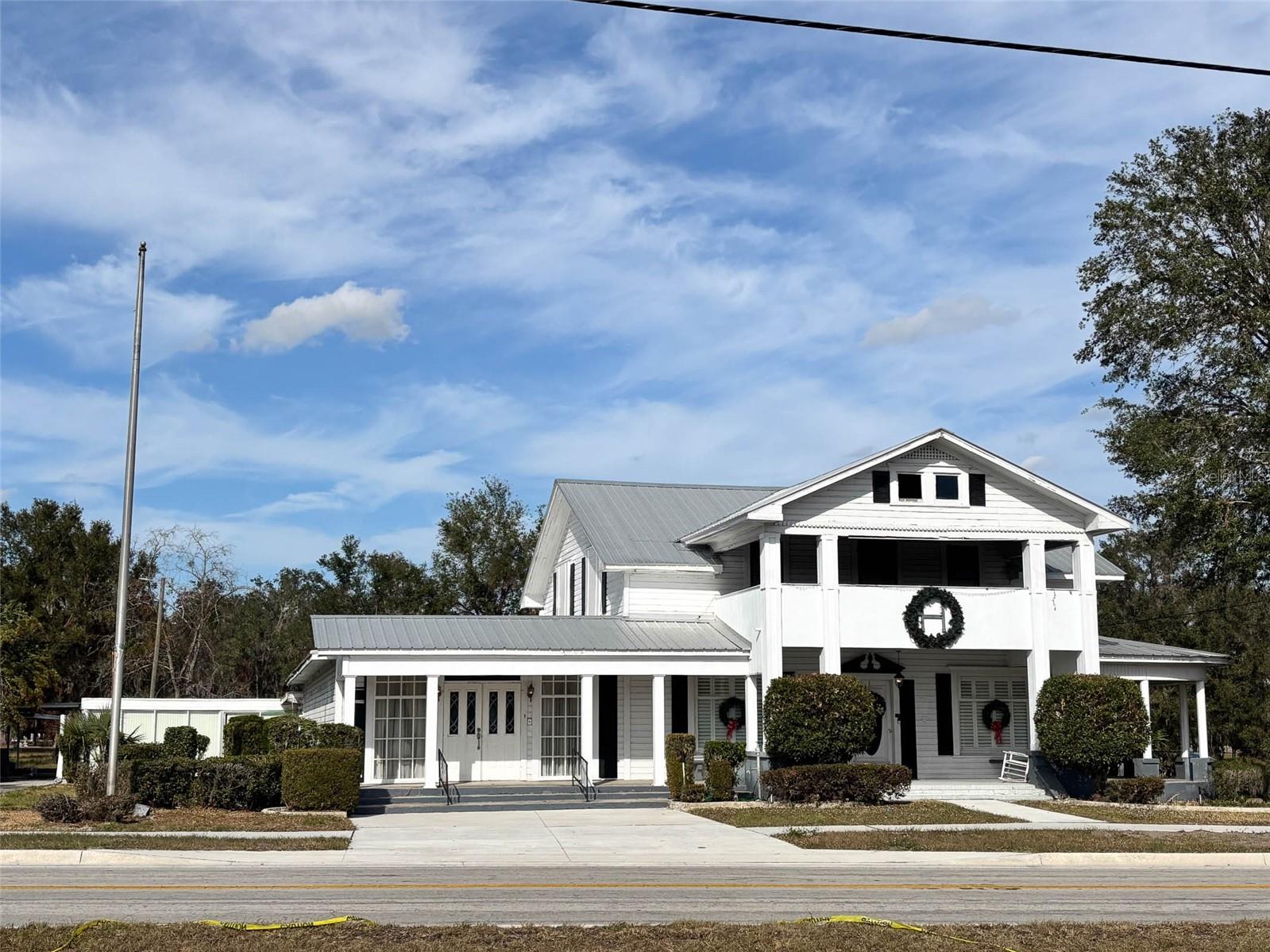 • Beautiful Victorian 2-story historic property in Ft. Meade FL.
• The property consists of a two-story building built in 1910 and expanded in 1964. The original structure
appears to have been a wood frame single-family residence with 2,785±sf. The chapel, display, apartment & garage was added in the early 1960’s. The building area is estimated at 5,000±sf, plus
3,256±sf in covered areas, including an 8’ deep wrap around porch, garage/tool room and 2 carports.
• Zoning is Commercial-1; Neighborhood Commercial, City of Ft. Meade
• Located on 0.91± acres
• City Utilities, Propane, irrigation,
• Perfect for a multi-use facility, venue facility, law office, church, medical office or your home business!
• Located at the corner Broadway & Washington Ave., the original stopping point for the town trolley!
• Lovely wrap around porch, inviting entryway foyer with chandelier lighting as well as multiple fireplaces, chair rail and crown molding, all adding to the warmth of the property.
• There is an apartment located on the back of the main building.
• Excellent location, across the street from the upcoming city venue center!
• New metal roof in 2018 as well as the rubber membrane over the chapel and back patio.
• 4 bedroom & 1 bath upstairs, the office has a closed off original fireplace that now uses gas.
• 265±’ frontage on Broadway Ave. 197±’ frontage on Washington Ave.
• The property consists of a two-story building built in 1910 and expanded in 1964. The original structure appears to have been a wood frame single-family residence with 2,785±sf. The chapel, display, apartment & garage were added in the early 1960’s. The building area is estimated at 5,000±sf, plus 3,256±sf in covered areas, including an 8’ deep porch, garage/tool room and 2 carports.
• The original 3rd story burned in the 1920’s.