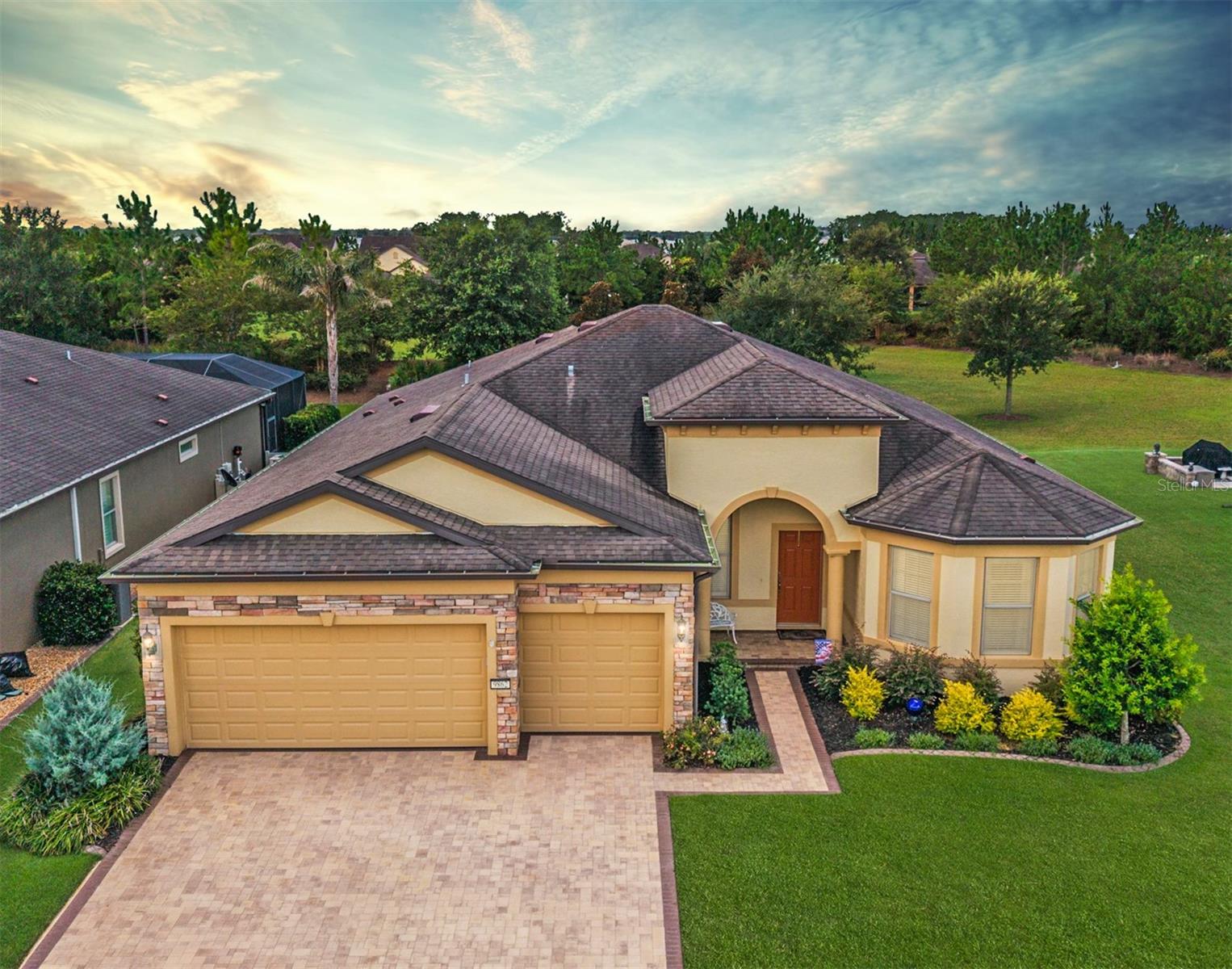 Don’t miss your opportunity to claim this spacious Pinnacle model, ideally positioned on a premium lot overlooking a peaceful, tree-lined greenbelt in the gated 55+ Stone Creek Golf Course Community. This home offers the perfect blend of comfort, functionality, and an active adult lifestyle—all in a setting that feels like a year-round getaway. From the moment you arrive, the curb appeal is undeniable—mature landscaping, decorative concrete curbing, stacked stone accents, and a paver-lined driveway create a welcoming first impression. Inside, this spacious home offers something for everyone, including a versatile bonus den or office and an extended 3-car garage with ample space for a golf cart, workshop, or hobby area. Step into a bright and inviting space where the open layout begins with a welcoming foyer and flows into a beautifully lit interior featuring high ceilings, subtle recessed lighting, and tile flooring in calming neutral tones set on the diagonal. The Chef’s kitchen is thoughtfully designed with everyday living in mind, featuring an oversized island that’s great for casual meals or catching up with friends. Granite countertops, a tiled backsplash, stainless steel built-in appliances, and a roomy walk-in pantry make it as practical as it is welcoming. The kitchen connects seamlessly to the spacious gathering room, offering an easy flow for everyday living and entertaining. Panoramic recessed sliders open wide to a large screened-in patio—an ideal spot to relax, host a gathering with friends, or simply enjoy the quiet beauty of the greenbelt views. The Owner’s suite is a private retreat, offering a large walk-in closet and an elegant en suite bath with a granite-topped double vanity and a glass-enclosed walk-in shower enhanced by a transom window for natural light. Both guest bedrooms include walk-in closets, and the front guest suite features a charming bay window and a private bath, providing comfort and privacy for visiting friends and family. This home is more than just a place to live—it’s a gateway to the vibrant lifestyle that Stone Creek is known for. Enjoy access to a championship golf course, resort-style pools, a full-service health spa, social clubs, entertainment, excursions, and so much more.