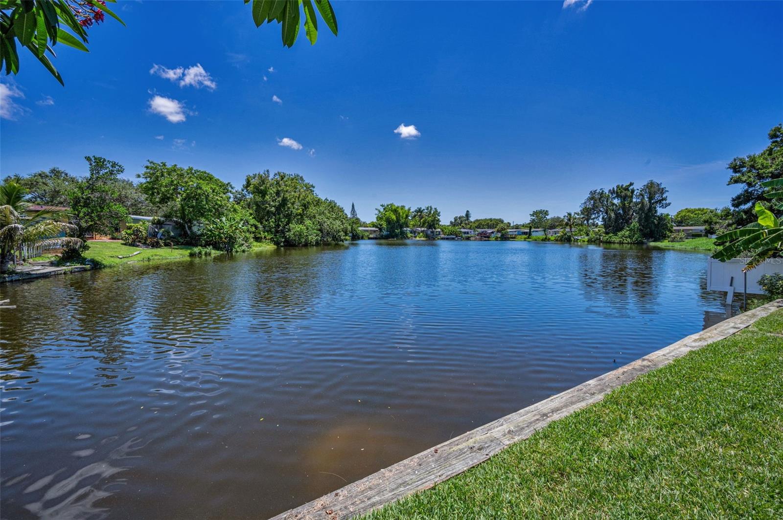 One or more photo(s) has been virtually staged. WATERFRONT LIVING AT ITS BEST! From the moment you walk through the front door, you're greeted by STUNNING VIEWS OF A SPRING- FED LAKE that stretch across the spacious Florida Room and Family Room. Walls of windows flood the home with natural light, bringing the outdoors in and creating a serene, sun-filled atmosphere.
The REMODELED KITCHEN features beautiful cream wood cabinets, bronze hardware, and a convenient PASS THROUGH-BAR— connecting to the Family Room while maintaining a warm, traditional layout (not open concept).
The SPLIT BEDROOM FLOORPLAN offers privacy and space, with a relaxing PRIMARY SUITE that includes a remodeled bath, two ceiling fans with remotes, and a HUGE WALK-IN CLOSET THAT FEELS LIKE ITS OWN ROOM.. One oversized guest bedroom provides the flexibility to be used as a media room or home office.
You’ll also love these many features: * DURABLE METAL ROOF *UPDATED GUEST BATH and MASTER BATH *WOOD FLOORING IN MAIN AREAS; CARPET IN BRs & FLORIDA ROOM *NEW WINDOWS, BASEBOARDS, & INTERIOR DOORS *POPCORN CEILINGS REMOVED, FRESHLY PAINTED INSIDE & OUT *CEILING FANS and LIGHT FIXTURES UPDATED THROUGHOUT *FENCED YARD w/LUSH NEW SOD and SPRINKLER SYSTEM USING RECLAIMED WATER *LARGE STORAGE SHED, GUTTERS, and AWNINGS *PRE-WIRED FOR A GENERATOR *NEW SEAWALL (2019), ELECTRICAL BROUGHT UP TO CODE (2016), TRANSFERRABLE PEST CONTRACT *LOCATED IN FLOOD ZONE X (no flood insurance needed)..
All of this in a PRIME LOCATION with easy access to I-275, DOWNTOWN ST PETE, AWARD-WINNING BEACHES, SHOPPING, and DINING.
This move-in ready home offers lakeside tranquility with everyday convenience — A MUST SEE!