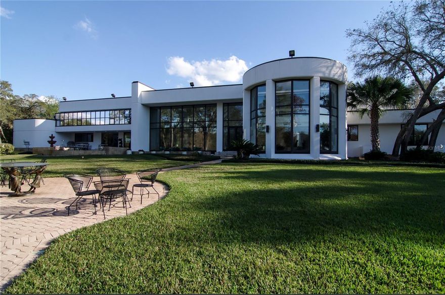 Behind the guarded gates of Sweetwater Club, 812 Sweetwater Club Blvd presents a rare resort-style compound offering 11.9 acres of privacy with its own private lake. A long, tree-lined approach opens to glass-lined living spaces created for grand entertaining and everyday comfort, complemented by a separate guest house, pool house, and expansive motor courts. Inside, soaring volumes and walls of windows frame water and greenspace views; outside, a lakeside entertaining deck, resort pool & spa, and a professional tennis court deliver an unmatched at-home lifestyle. The flexible bedroom configuration—multiple ensuite options with bathrooms designed by Sheryl Wagner and generous secondary rooms—supports multi-generational living, staff quarters, or long-term guests. Thoughtful details include abundant natural light, multiple gathering rooms, caterer-friendly service areas, and seamless indoor–outdoor flow for hosting. Enjoy the convenience of nearby golfing, shopping/dining along SR-434/I-4, and outdoor recreation at Wekiwa Springs State Park—all within highly regarded Seminole County schools (buyer to verify). A spectacular kitchen with St Charles cabinets and a generous island with seats.  A singular opportunity to secure scale, privacy, and amenities seldom available in Central Florida. Shown by appointment only. All measurements, features, and school zones are approximate and subject to buyer verification.