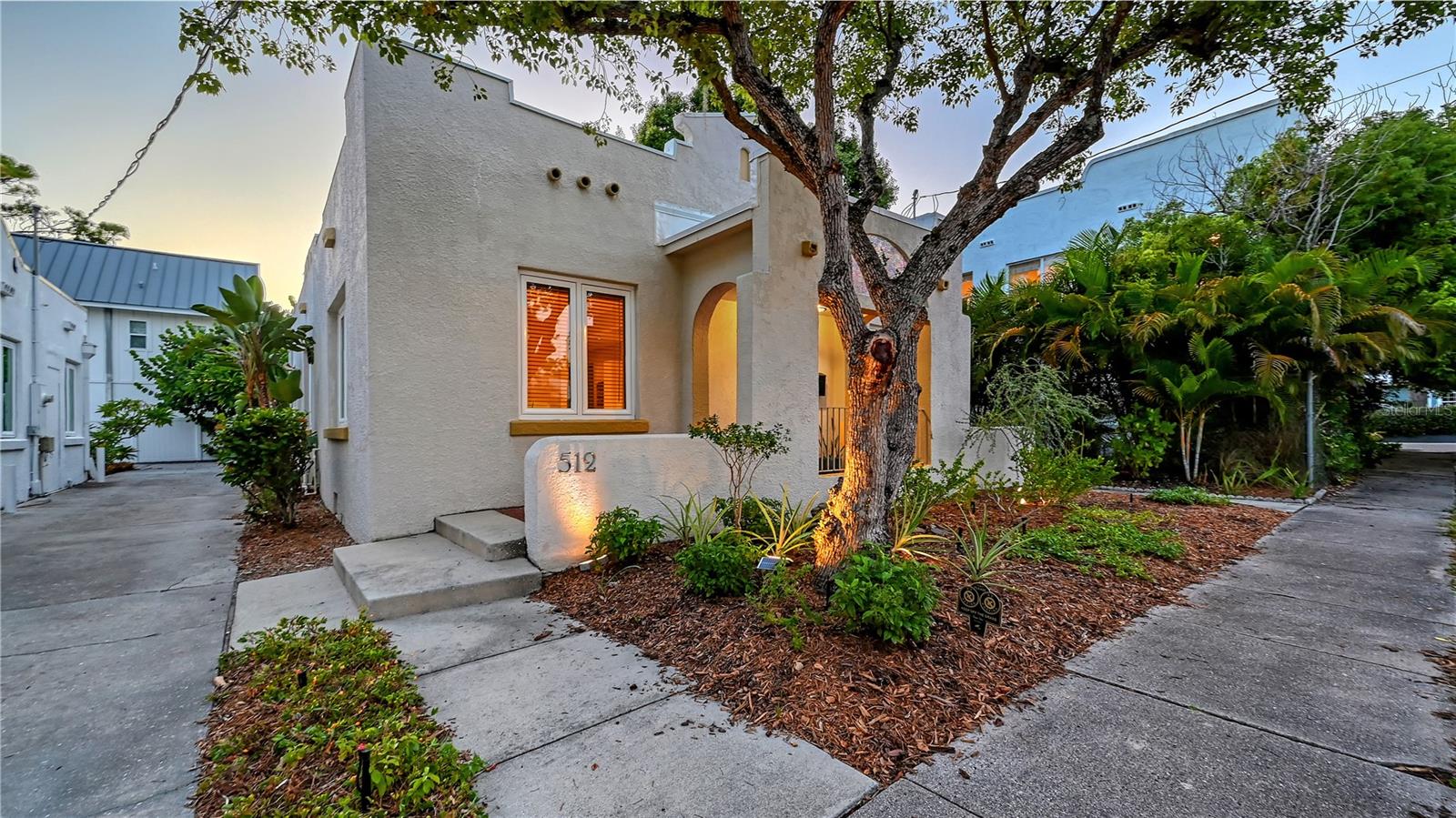 Step into Sarasota’s history reimagined for modern living. This extraordinary 1922 Spanish bungalow, located in the sought-after Owen Burns neighborhood of Laurel Park, has been thoughtfully renovated by architect Dale Parks to blend original charm with contemporary comfort. With major updates including a new air-conditioning system (2019), Thermoplastic Polyolefin roof (2018), and impact windows and doors (2020), this residence offers peace of mind alongside timeless design. Inside, the home opens with a skylight and a distinctive free-standing deco wall, creating an airy and light-filled entrance. The open layout flows with oak floors through the living and dining rooms, where abundant windows invite in natural light. The kitchen, connected to the dining area, is designed with efficiency in mind and offers a warm, welcoming space for everyday cooking and casual gatherings. Both bedrooms are generously sized, with the primary suite serving as a wonderful retreat. A large walk-in closet anchors the room, while the en-suite bathroom includes an oversized soaking tub, separate walk-in shower, and dual vanity area. The guest bedroom offers equal comfort and flexibility, making it ideal for visitors, a home office, or creative space. A spacious laundry room leads to the private outdoor patio, designed in for relaxing mornings or evening entertaining. The landscaped backyard, complete with tropical plantings, newer landscape lighting, and winding pavered pathways, provides a serene, low-maintenance setting. This historic property is a rare alternative to downtown condo living—delivering privacy, character, and the freedom of single-family ownership while being just moments from Sarasota’s vibrant cultural core. Living in Laurel Park means being at the center of Sarasota’s most exciting offerings. From your doorstep, enjoy a short walk or bike ride to theaters, galleries, boutiques, and an array of dining options. Stroll to the Saturday farmers market, explore the Bayfront, or head to nearby beaches including Lido Key and Siesta Key. With its combination of architectural design, modern updates, and unmatched location, this home represents downtown Sarasota living at its most unique and desirable.