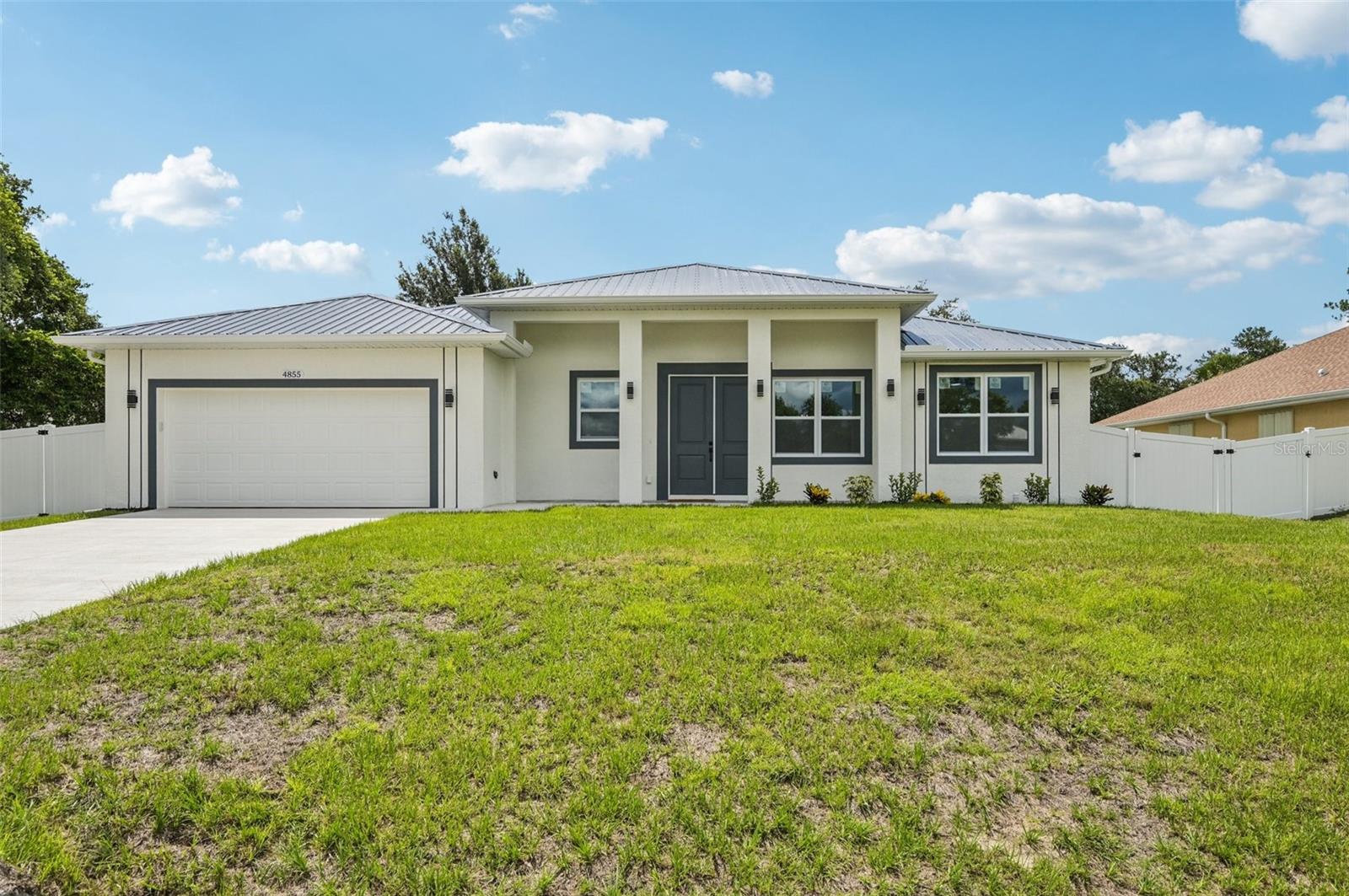 This beautifully crafted, Move In Ready new construction 3-bedroom, 2-bathroom concrete block home with a 2-car garage offers the perfect blend of style, durability, and energy efficiency. Featuring a metal roof, impact-rated windows, doors, and garage door, this home is also Florida Green Building Coalition Gold Certified, ensuring lower insurance premiums and long-term savings. Step inside to an open floorplan with 10-foot ceilings, 8-foot doors, and tile flooring throughout. The kitchen showcases solid wood soft-close cabinets, garbage disposal, granite countertops, and modern hardware, all illuminated by energy-efficient LED lighting. Enjoy added privacy with a fenced yard and peace of mind knowing you're in a NO flood zone. Completed with a builder warranty, this home is the ideal combination of comfort, quality, and lasting value. Available now!