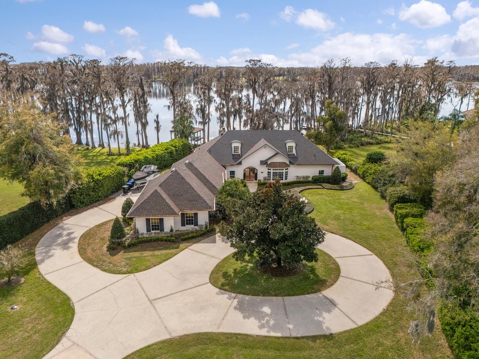 BRAND NEW ROOF 2025! LAKEFRONT! Prepare to be amazed by this exquisitely renovated estate home with a BRAND NEW HEATED Infinity Pool, perfectly nestled on the tranquil shores of Lake Cypress near downtown Windermere. Set on 1.2 acres with 100 ft of lake frontage, this luxurious residence boasts an attached guest house and an array of high-end features. Live each day watching sunsets and seeing Disney Fireworks directly off your private dock. As you arrive, the expansive driveway leading to the three-car garage provides ample space for family and guests, making it ideal for large gatherings.
Step through the grand solid wood double doors and be immediately captivated by breathtaking lake views. The entryway, adorned with hand-crafted woodwork, sets the stage for the home’s warm and inviting ambiance. Just beyond, the spacious family room features a cozy wood-burning fireplace and large picture windows, allowing natural light to flood the space.
The heart of the home is the showstopping French-inspired kitchen, a true masterpiece. This culinary haven boasts light cabinetry, stainless steel Viking appliances—including a pot filler—an oversized island, ample storage, a subway tile backsplash, a charming brick accent wall, and ambient lighting. A hidden gem within the kitchen is the generously sized butler’s pantry, highlighted by repurposed 1800s wooden doors that add character and history to the space.
Designed for both formal and casual entertaining, an additional living area features a fully equipped wet bar and a cozy gas fireplace, perfect for unwinding. Continuing with the French-inspired elegance, the primary suite is located on the first floor, offering a private patio with serene lake views. The en-suite bath is a true spa retreat, featuring a freestanding soaking tub, marble-like tile flooring, a rain showerhead and spacious Walk-in Closet with Custom built in features. As you move through the home, don’t forget to admire the custom coffered ceilings and exquisite lighting fixtures. Additionally on level one you will have a pool bath with a private sauna tucked right off the pool; a literal health and wellness home.
Upstairs, two additional bedrooms are thoughtfully positioned at opposite ends of the home, each with its own en-suite bath—providing a private and welcoming retreat for family or guests.
Step outside to your gorgeous backyard oasis and take in the spectacular lakefront setting. Whether enjoying a morning coffee as the sun rises or dining al fresco while watching the sunset, this outdoor space offers the ultimate in relaxation. Adding to the home’s allure is a private boat dock with a lift, allowing you to enjoy boating, fishing, and water sports just steps from your door.
The excitement doesn’t stop there! This estate also features a brand-new infinity pool, offering the perfect spot to cool off while enjoying the stunning lake views.
For additional comfort and convenience, the property includes a two-bedroom, one-bathroom guest house. With its own private entrances, spacious walk-in closets, and a beautifully designed full kitchen, this guest retreat is as elegant as the main residence. Your visitors will love the warmth of the wood flooring and the soothing sounds of the lake just outside their door.
This exceptional home must be experienced in person to truly appreciate the thoughtfulness and craftsmanship in every detail. Enjoy the Disney Fireworks glistening over Lake Cypress Each night!