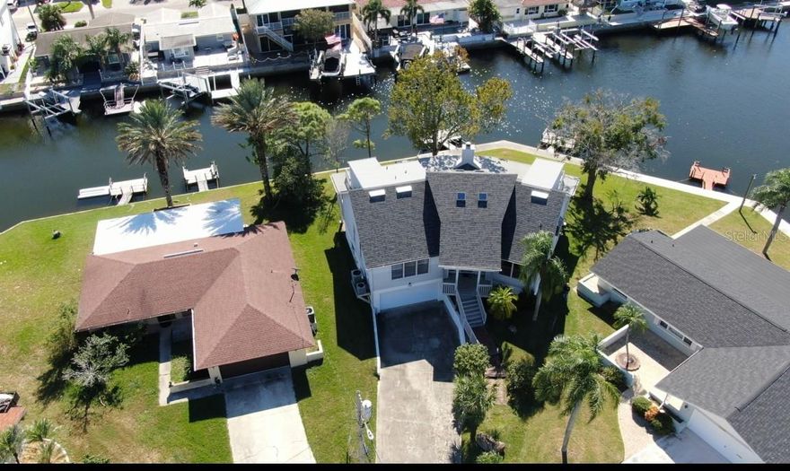 This Key West style Elevated home did not flood during hurricane Helene.  It boasts 131’ of seawall frontage on the deep South Channel with direct access to the gulf.  The first floor has 1 bedroom, 1 full and 1 half bath, a large office/den, eat-in kitchen with breakfast bar and a dining room.  The large living room is open to the second story ceiling and has a wood-burning fireplace for cool evenings.  Sliders from the living room open to a covered deck spanning the entire length of the back of the home.  The second floor has 2 bedrooms each with their own open decks facing the water.  The bedrooms are connected by a loft that also serves as an office, or library and overlooks the living room below.  There is 1 full bathroom on the second floor.   The combination of high wooden ceilings with four skylights creates an open casual feeling to the home.  The roof was replaced in 2024.  The garage is set up for the boater with garage doors on the front and back of garage for easy access to boating equipment.  The unfinished basement is perfect for storage, or for that wine cellar you dreamed of.  Gulf Harbors is a golf cart friendly community.  There is an optional community HOA that hosts activities and clubs throughout the year and a members-only private community beach with unforgettable sunsets. If you are looking for the Florida Lifestyle, look no further!