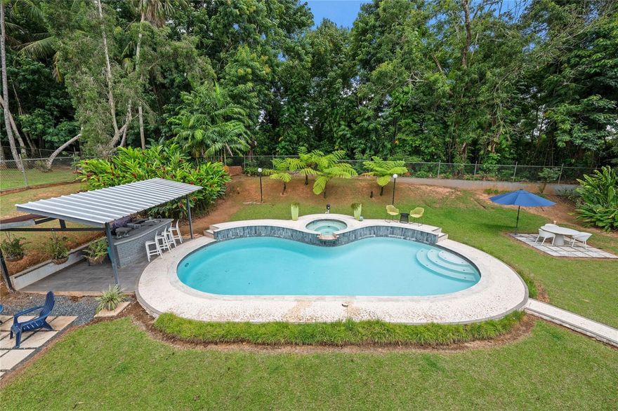 Discover the perfect blend of city convenience and tranquil countryside living in this beautiful one-story home in Lomas del Sol, Guaynabo. This property offers the best of both worlds—easy access to urban life while being surrounded by nature, lush vegetation, and fresh breezes.
Situated on an expansive 2,182 m² lot, this contemporary residence boasts 1,864sq ft. The property features impressive outdoor oasis great for entertaining. The interior showcases an open-concept layout, including a living room, dining area, an inviting family room, and kitchen with top-of-the-line appliances. The house spans three bedrooms with two bathrooms, and a powder room, additionally two flex rooms currently used as an office and storage room, convertible to a private apartment. 
Enjoy resort-style amenities including a Salt Water Pool with an Inverter Motor, an outdoor bar with BBQ area, and a fire-pit or lechónera. Designed for comfort and sustainability, the property is fully equipped with a 12k Generator, 23 Solar Panels, 2 Tesla batteries, and a Solar Water Heater. This home invites you to live a lifestyle that seamlessly combines nature, comfort, and convenience. Don’t miss this rare opportunity, call today to schedule your private showing!