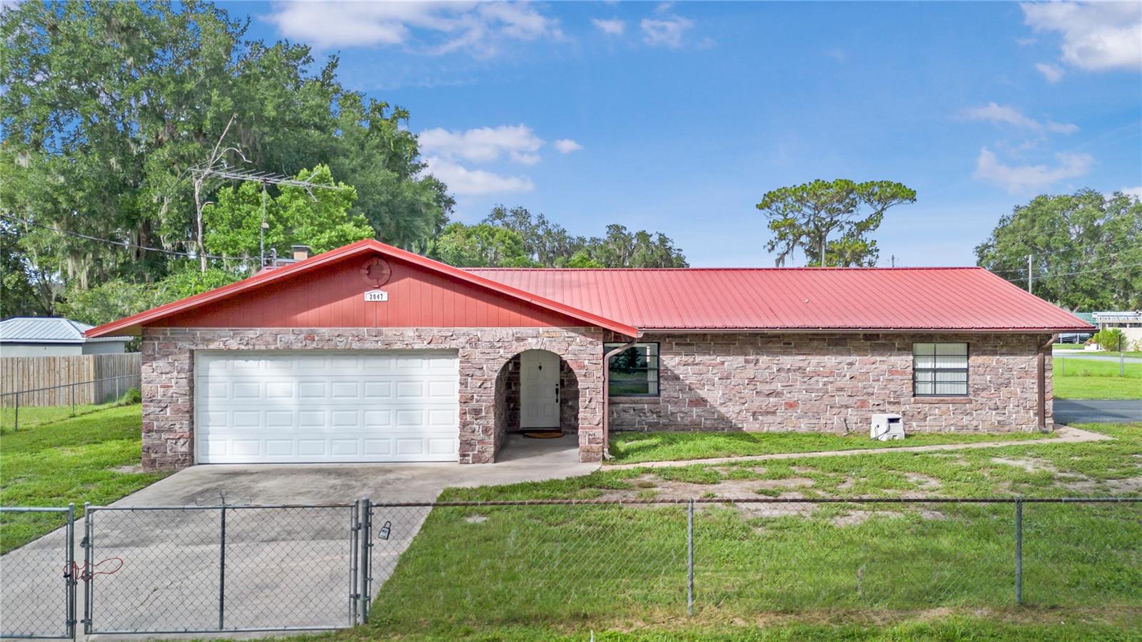 Discover this charming two-bedroom, two-bathroom block, faux brick home, ideally situated on a spacious corner lot in the highly sought-after Tracy’s Point neighborhood of Lake Panasoffkee. Fully fenced with two driveways and a two-car garage, this property offers both privacy and convenience. The home features a durable metal roof installed in 2005, an HVAC system from 2005, and a water heater updated in 2018. Enjoy cozy evenings by the electric fireplace or relax in the enclosed lanai. The kitchen is complete with an eat-in bar, a built-in oven and upgraded appliances. The garage is equipped with a slip resistant rubber floor covering, a split mini-AC unit, a ceiling fan, and houses the laundry for added functionality. Spanning over a quarter of an acre, the expansive yard provides ample space for outdoor activities. Perfectly located between Lake Panasoffkee and the Withlacoochee River, and just off I-75, this home offers quick access to the Gulf Coast, as well as proximity to the turnpike for easy travel to amusement parks and airports. Don’t miss the opportunity to own a piece of this premier lakeside community!