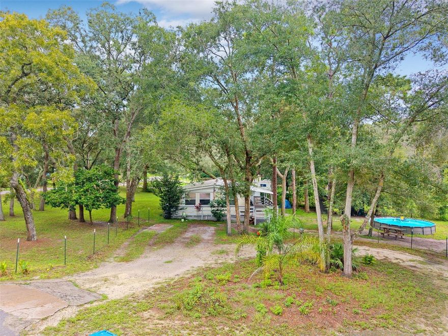 $15,000 PRICE REDUCTION!!! MOTIVATED SELLERS!!! 
OWN YOUR OWN SLICE OF PEACE OVER 1/2 ACRE!
**Country Living in Dade City – .54 Acres, No HOA!** BRING YOUR DOGS, BOATS, HOT RODS, CHICKENS!!!! 
SELLERS DO NOT PAY FOR FLOOD INSURANCE. NO FLOOD INSURANCE REQUIRED!!!!

Discover peaceful living on this spacious **.54-acre lot** surrounded by mature trees and natural beauty. This charming 3-bedroom, 1-bath home offers plenty of room to spread out, complete with a large fenced yard perfect for pets, gardening, or enjoying the outdoors.
Step onto the inviting front porch and relax in the shade or entertain friends and family. The property includes an above-ground POOL perfect for summer fun, a picnic area, and ample space to park your boat, RV, or other toys – all with **No HOA restrictions**. Located on a quiet road, you’ll enjoy the tranquility of country living while still being just minutes from downtown Dade City, local shops, dining, and schools. Less than 1 hour from Tampa & Orlando. Less than 30 minutes from Downtown Dade City & Zephyrhills. Metal Roof & AC (4/5 yrs old).
 **Key Features: Covered front porch, above-ground pool, fully fenced yard with storage shed, wrap-around driveway, plenty of space for RV/boat parking, and no HOA or deed restrictions.
Bring your imagination and make this property your own private retreat in the heart of Dade City! Give us a call for a simple way of life!