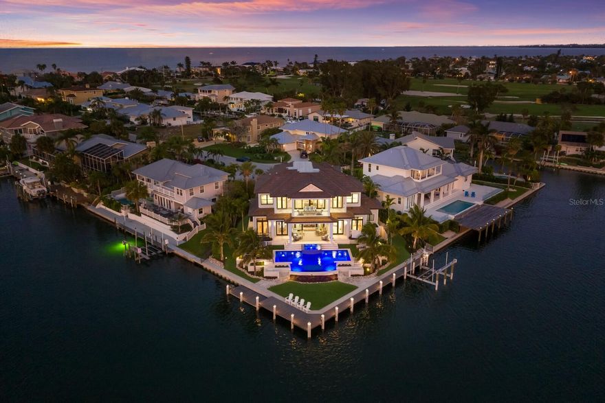 Stunning Key Royale Waterfront.  One of the finest homes on the island and a boater's paradise.  Meticulous attention to every detail in this exquisite waterfront custom coastal home.  From state-of-the-art construction to impeccable finishes to stunning outdoor areas, the features are endless. Be captivated by the endless wraparound 270-degree water views from virtually every room; enjoy the flowing design offering fabulous entertaining and gathering areas; and appreciate the privacy of an all en-suite design. Even the designer furnishings, indoors and out, and original artwork are included. The home is perfectly positioned to take advantage of the inviting outdoor spaces, the well-protected crystal waters of Bimini Bay, and the ever-spectacular sunsets. The heated saltwater infinity pool, complete with spa, seemingly plunges into the bay; the composite dock wraps around 160 feet of brand-new seawall; and a 20,000-pound lift welcomes most any boat. Landscape lighting, micro-irrigation, and palm trees and coconuts all complement the tropical setting. Inside, be greeted by craftsman-style architectural detail throughout, including 12-foot ceilings, crown and profile moldings, intricate trim work and white oak plank flooring. The chef’s kitchen features Wolf and Sub-Zero appliances, gorgeous custom wood cabinetry,  natural stone center island, and walk-in butler’s pantry with wine refrigerator and sub-zero drawer refrigeration. The great room and dining rooms both open to the outdoors with endless water views and both feature custom and designer furnishings. All four bedrooms are en-suite and all four feature custom and designer furnishings as well. The owner’s suite on the main level looks out to Bimini Bay and features a spa-inspired bath and shower, walk-in closet with built-ins, and a dual sink vanity. Three generous guest suites on the upper level all feature private baths, built-in closets and gorgeous water views. The upper level also hosts a relaxing furnished gathering and media area with wet bar and smart TV. For those amazing over-the-water views, the upper-level lanai has one of the best sunset views on the island. Also, on the upper level, the large office/study has plenty of space for two or could double as a fitness room or use as a fifth bedroom. Throughout, you’ll find impact windows and doors, the latest in smart home technology, and built-ins to name a few. Other features include gas cooking, whole-house tankless water heater, commercial garage door opener and epoxy flooring, full-size hydraulic elevator, Trane XL air conditioning, integrated electric shades, plantation shutters and more. The North Point neighborhood in Key Royale offers privacy, yet offers convenience to the island's white sand beaches, infinite number of restaurants, multitude of shops, and more. Boaters will love the deep protected waters of Bimini Bay with no bridges and easy access to the Intracoastal, Anna Maria Sound, Tampa Bay, and the Gulf of Mexico.   Exquisite waterfront coastal architecture. Thoughtful design. Meticulous attention to every detail. Designer furnishings. Boater's paradise. Easy access. This truly is one of the finest homes on the island.
