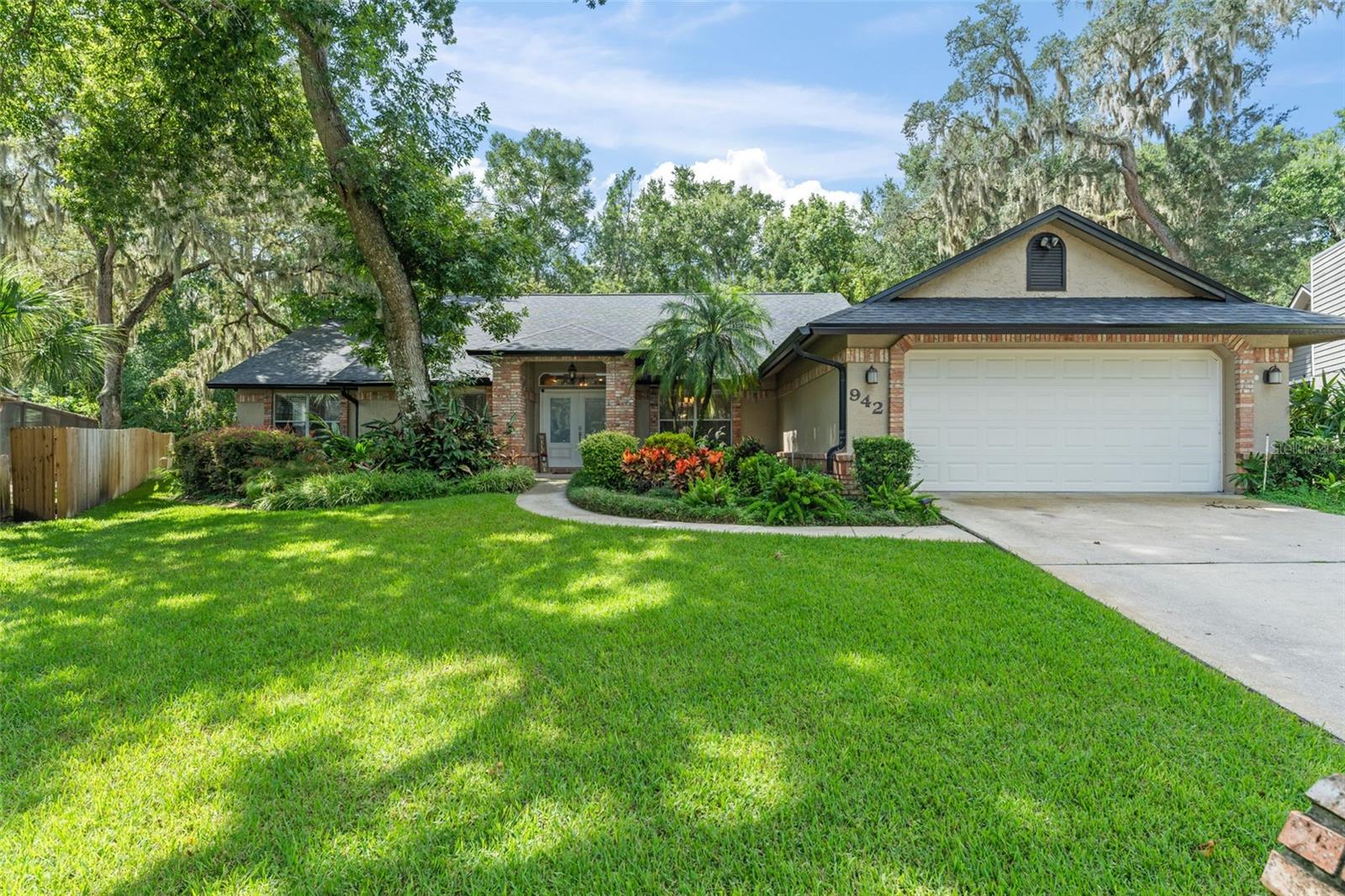 **This property qualifies for a closing cost credit up to $10,100 through the Seller’s preferred lender.** Tucked away in one of Longwood’s most beloved neighborhoods, this beautifully maintained 4-bedroom, 2.5-bathroom single-family home sits on nearly half an acre and offers 2,424 square feet of thoughtfully designed living space. Surrounded by nature and nestled in a gated community that truly embraces outdoor living, this property offers not only a place to call home—but a lifestyle. From the moment you arrive, the manicured front yard greets you with elegant landscaping, a mature shade tree, and charming French Quarter-style doors that beckon you inside. Step through the entryway and you’re immediately welcomed by a blend of tile and wood flooring, vaulted ceilings, and an abundance of natural light. To your right, a formal dining room invites memorable meals and special gatherings. To your left, a flexible living space—currently home to a pool table—features beautiful wood cabinetry and endless potential for entertainment or relaxation. Straight ahead, the heart of the home opens up to a warm and inviting family room with vaulted ceilings, two skylights, and a cozy brick fireplace—the perfect spot to gather on cool winter nights. French doors with sidelights draw your eyes out to the spacious screened-in patio, while nearby, a charming breakfast nook with a bay window offers views of the backyard and morning sunrises. The kitchen is as functional as it is welcoming, featuring wood cabinetry, stainless steel appliances, and easy access to the dining room for effortless hosting. The split-bedroom layout offers privacy and convenience. On one side of the home, the primary suite welcomes you through double doors with high ceilings, glass-paned doors leading to the patio, and a luxurious ensuite bathroom. The bathroom features a sunken drop-in tub, dual vanities, a walk-in shower with floor-to-ceiling tile, and mirrored closet doors—your own peaceful retreat. A guest bedroom and nearby half bath sit conveniently on this side of the home as well—ideal for guests or a home office. On the opposite side, two additional guest bedrooms with built-in closets share a full bathroom with dual vanities, a walk-in shower, and direct access to the patio—perfect for future pool plans or easy indoor-outdoor living. Step outside and enjoy the expansive screened-in patio—a blank canvas for dining, lounging, or entertaining. The fenced backyard is lined with a privacy wall and offers wide grassy areas on both sides of the home, ideal for pets, play, or garden dreams. But what truly sets this home apart is its community. Residents enjoy exclusive access to a private dock perfect for kayaking adventures that lead directly to the scenic Wekiva River and onward to the beloved Wekiva Island. There's even a dedicated kayak storage area near the dock and playground—making it easy to enjoy spontaneous days on the water without the hassle. On top of this amazing community amenity you’ll also be a short distance to Riverbend Park that offers tennis courts, basketball courts, a baseball Diamond, eating pavilion and playground. As well as deeded access to Sweetwater Beach that gives you direct access to Lake Brantley with a playground and swimming area. Whether you’re looking for a peaceful forever home, a family-friendly neighborhood, or a nature lover’s paradise, 942 Deerwood Loop offers a rare blend of comfort, community, and connection to the great outdoors.