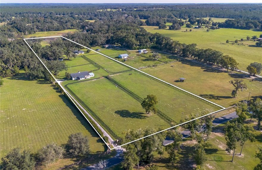 Situated amongst large beautiful horse farms in Marion County’s vibrant Horse Country just 4 miles from the World Equestrian Center (WEC), this 12.71-acre farm is a real gem. Beyond a gated entry and down a paved driveway, the property offers a lovely center aisle barn, a total of 5 paddocks with board fencing and nice, flat areas. The 9-stall concrete block center-aisle barn includes wash stalls/grooming stalls, an equipment and work area, as well as a new tack room / riders lounge with a full bath and laundry area. Near the main home, a newly constructed 2-stall concrete block barn includes its own wash area and tack/feed room. A 30-amp RV hookup with septic connection adds further convenience for guests or seasonal rental income. Towards the back of the property is a thoughtfully updated 3-bedroom, 2-bath home built in 1985. Spanning just under 3,000 sqft, the home features a split-bedroom floor plan, tall ceilings, and engineered hardwood flooring and tile in the kitchen and baths. The spacious great room features a lovely brick accent wall with fireplace, large windows, cathedral ceilings, and an inviting formal dining area. Directly open to the great room, the kitchen is well equipped for those who enjoy cooking with stainless steel appliances, extensive cabinet storage, quartz countertops, and a large center island with breakfast bar. An additional breakfast nook with built-in shelving and window seat also provides stunning views of the surrounding farm and pool, perfect for a quiet morning coffee or less formal meals. Each bedroom is oversized and inviting, though the primary suite is the true stand-out with an extra large layout, walk-in closet, and private en-suite bathroom with an overflow tub and dual vanities. Additional features of note include a dedicated office for those who work from home and a spacious garage. At the back of the home is a large screen-enclosed pool deck with recently resurfaced in-ground pool and spa, a covered area for seating, and an adjacent open-air covered deck. An additional climate-controlled flex building with covered carport is also established on the property, ready to serve as a gym, workshop, studio, or office as desired. With its seamless blend of updated residential space and professional-grade equestrian infrastructure, combined with the abundant beautiful live oaks, this turnkey property offers a rare opportunity to train, ride, and live in comfort!