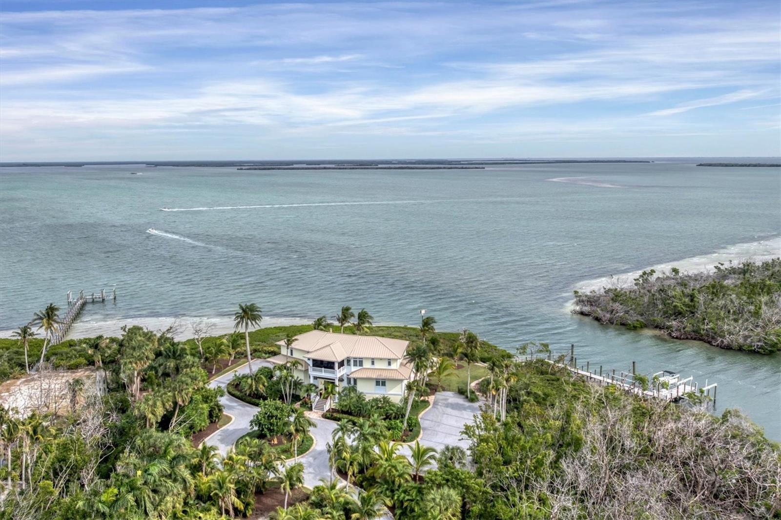 Very rarely does a property come along that truly takes your breath away. An aerial view immediately reveals the grandeur of the land, one the largest waterfront lots on the island of Boca Grande. Encompassing 3.5 acres of land and nearly 1.2 acres of submerged lands with 585 feet of direct deep water frontage, this resort-like compound is the perfect island getaway, with a 70ft+ deep water boat dock as well as two slips with boat lifts 20,000Lb and 6,000Lb, this is island living at it’s most spectacular. This custom home was designed to take advantage of the wrap around water views with master suite, kitchen and living area all on the very top floor accessible by grand staircase or 3 stop elevator. The first living level contains a large and inviting home office with closet and custom cabinetry, bar with granite counters and ice maker with Sub-Zero wine refrigerator with additional beverage drawers. Also on this floor are guest bedrooms, one set up as a gym, with custom en-suite bathrooms, laundry and water views everywhere including from a secondary living and gathering area. Enjoy the water facing screened porch with electric roll down shades as well as and open porch with gas grill plus a large and inviting screened porch off the kitchen also with electric roll down shades overlooking the manicured property with not another home in sight. With superior construction, this home was meticulously renovated in 2015 to include all Marvin impact windows and doors, all new reclaimed heart pine flooring, new baths and crown molding and custom mill work at every turn. A new metal roof was installed just this year! The kitchen includes granite counters, 48-inch Wolf Oven / Range, Sub-Zero side by side refrigerator, Sub-Zero Wine storage refrigerator and Miele dishwasher. 4 car garage, and waterfront pool with covered ground level deck and furniture will make you feel like you never have to leave this perfect slice of Boca Grande Florida paradise. Offered furnished with some art and personal exclusions.
