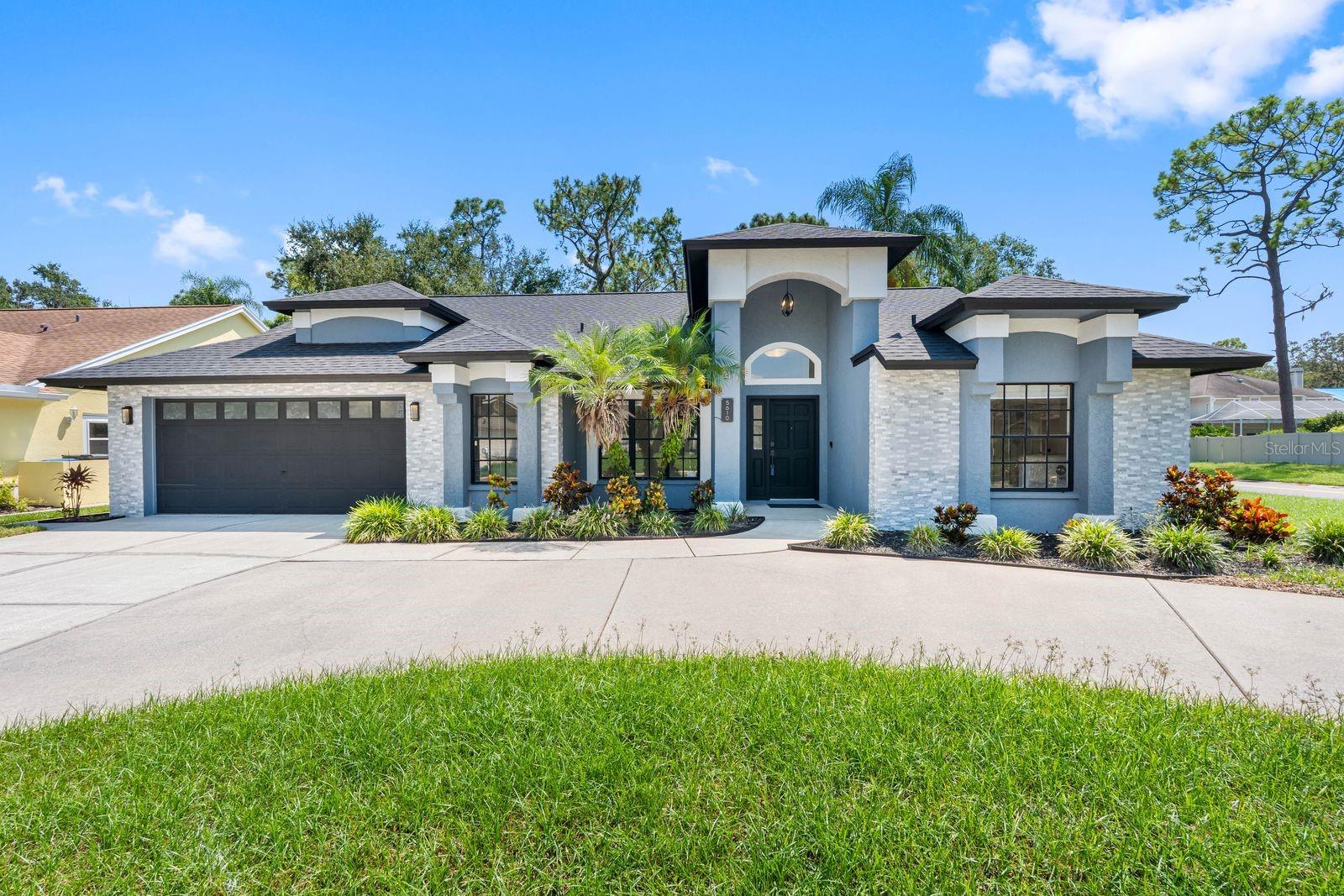 This well maintained former model home is situated on an oversized corner lot with very low HOA and no CDD! Upon arrival you will be greeted by mature tropical landscaping with palm trees, circular driveway and Wi-Fi security cameras. Some of the recent updates include roof, AC and tankless water heater. As you enter the open concept floor plan you will immediately notice the high ceilings with crown molding and abundance of natural light throughout. The formal dining room and sitting room features elegant pillars and built in display ledge. There’s neutral color tile floors in all main living areas and brand new plush carpet in the bedrooms. The living room with a cozy brick wood burning fireplace opens to an eat-in kitchen equipped with granite counters, peninsula, closet pantry, espresso cabinets, stainless steel appliances and a mobile island. The laundry room offers plenty of space and includes side by side washer and dryer. The massive primary bedroom features french doors, spacious walk in closet, and an en suite with a garden jacuzzi tub, separate walk in shower and double vanity. There are multiple sliding doors that lead to an expansive screen lanai boasting a full pool bath, heated in ground salt water pool, new turf area with ceiling fans and a big screen wall tv perfect for entertaining. The level back yard is fully fenced and has mature shade trees overlooking serene wooded views. This quaint community is conveniently located to all of what Tampa Bay has to offer!