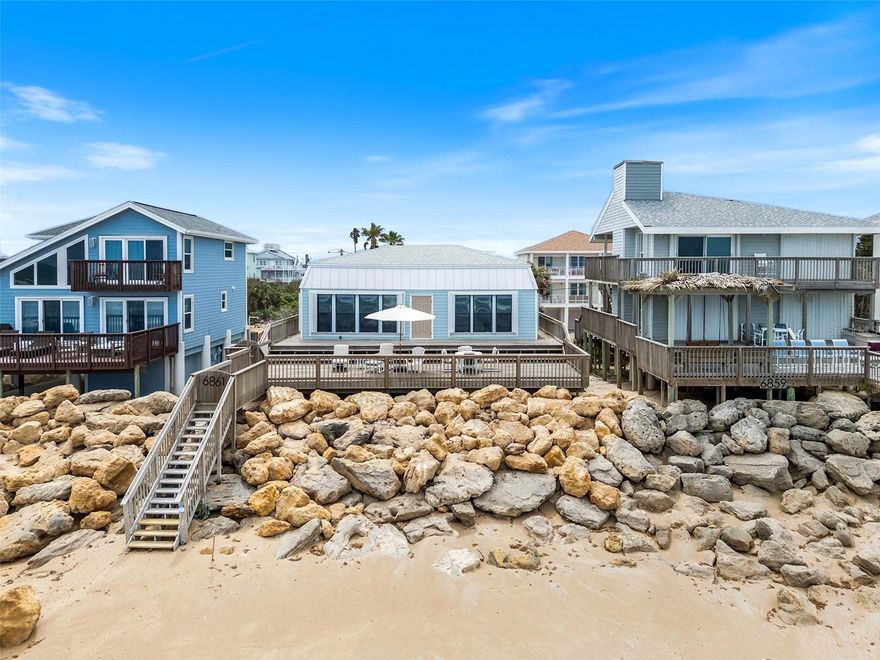 The Quintessential Beach Home! Be sure to check out the new and improved Rock Revetment (completed April 2026). This Bethune Beach home is perfectly situated overlooking New Smyrna's no-drive beach. Sitting High and Dry, you'll enjoy the breezes and views from the 900 Sq. Ft. (+/-) of elevated ocean front deck with private stairs down to the beach. Inside the home: You'll be welcomed by the understated coastal vibe. Casual, Open Floor Plan allowing for full beach and ocean views from Kitchen, Great Room and Primary Suite.  Downstairs is another Florida Room, two guest rooms and a guest bathroom. You'll appreciate the protection and security provided by the 2026 ENHANCED ROCK REVETMENT. The Beautiful, Substantial Revetment also offers an organic transition from deck to beach. Storm Shutters (new in 2024) allow for "lock and leave" peace of mind. Ocean Front Deck new in 2023. Roof new in 2022. A/C new in 2023. Hardie Board siding new in 2022. This Bethune Beach Gem offers a "turn key" opportunity to bring your toothbrush and start enjoying Beach Front Living! Pictures paint a thousand words, so please check out the photos and virtual tour to fully capture this special beach home. All measurements are approx., and Buyer responsible for verifying all dimensions.