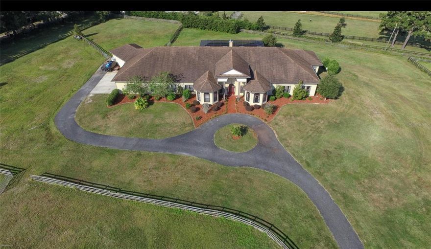 Welcome to Hilltop Estate  where you can live the Premiere Equestrian Lifestyle complete with 10.23 incredible acres located in the equine community of Pinnacle Park featuring a stunning 8160 Sq. Ft. home with 6 bedrooms and 4 1/2 baths and a large spacious 4 car garage!  The home and grounds have been meticulously maintained offering privacy and serenity just minutes from HITS and WEC!   There are so many custom features in this home including soaring 12 foot ceilings,  stunning wood beams, crown molding, granite, 5,000 sq. ft. of imported tiles, 3-5 ton AC units and all wrapped in hardboard siding. Elegantly updated a grand foyer leads to the open floor plan featuring a spacious Livingroom w/ gas fireplace and plenty of natural lighting, gourmet kitchen, stainless steel appliance and large pantry make it perfect for entertaining or daily use, private office with bay window allows you to enjoy the view, master bedroom and spacious sitting area with your own private wet bar!  Updated Ensuite bath for a real spa retreat at the end of a day.  Enjoy your screed solar heated pool and spa along with a rock waterfall feature.  New roof, water heater landscape lighting, whole house surge protection and a whole house generator,  security system, and Star Link Wi-Fi!  Designed for the modern family combining luxury living with functional design.  This farm has beautiful rolling hills, wood fencing,  and 5 paddocks with access to the riding trails throughout the community.  If you are seeking a slice of Ocala paradise this one checks all the boxes.  Contact us for a showing today!