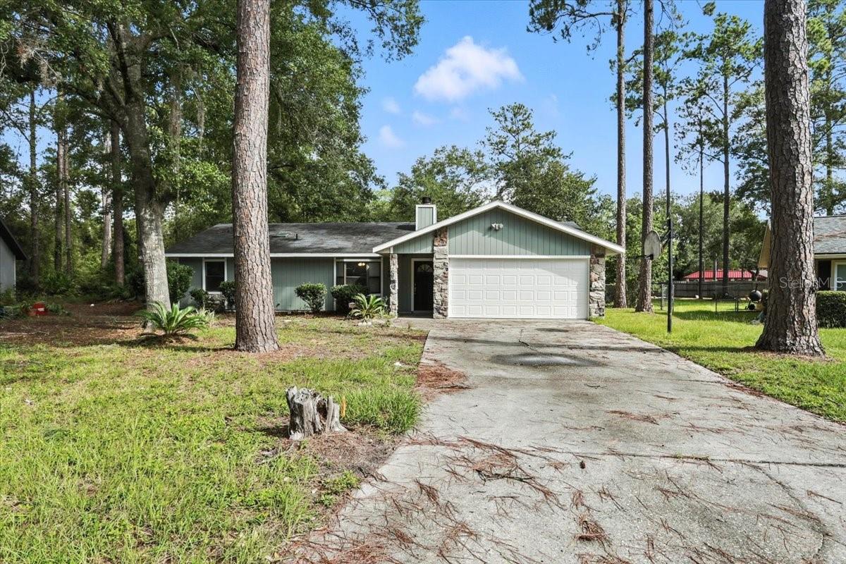 This move-in ready home sits on 0.52 acre, the largest lot in the neighborhood. It features new luxury vinyl plank flooring throughout, fresh interior/exterior paint, a new garage door and opener, and a remodeled kitchen with granite countertops, new cabinets, stainless steel appliances, and subway tile backsplash. Vaulted ceilings, wood-burning fireplace, bay window, and a bright open layout add charm and functionality.
Primary suite includes updated bath with new vanity, tile, and fixtures. Split floorplan offers two additional bedrooms and a renovated hall bath. Large indoor laundry room with skylight and extra storage. 2-car garage. No HOA. Backs to Norton Elementary. Close to UF, Santa Fe, VA, UF Health, and shopping!