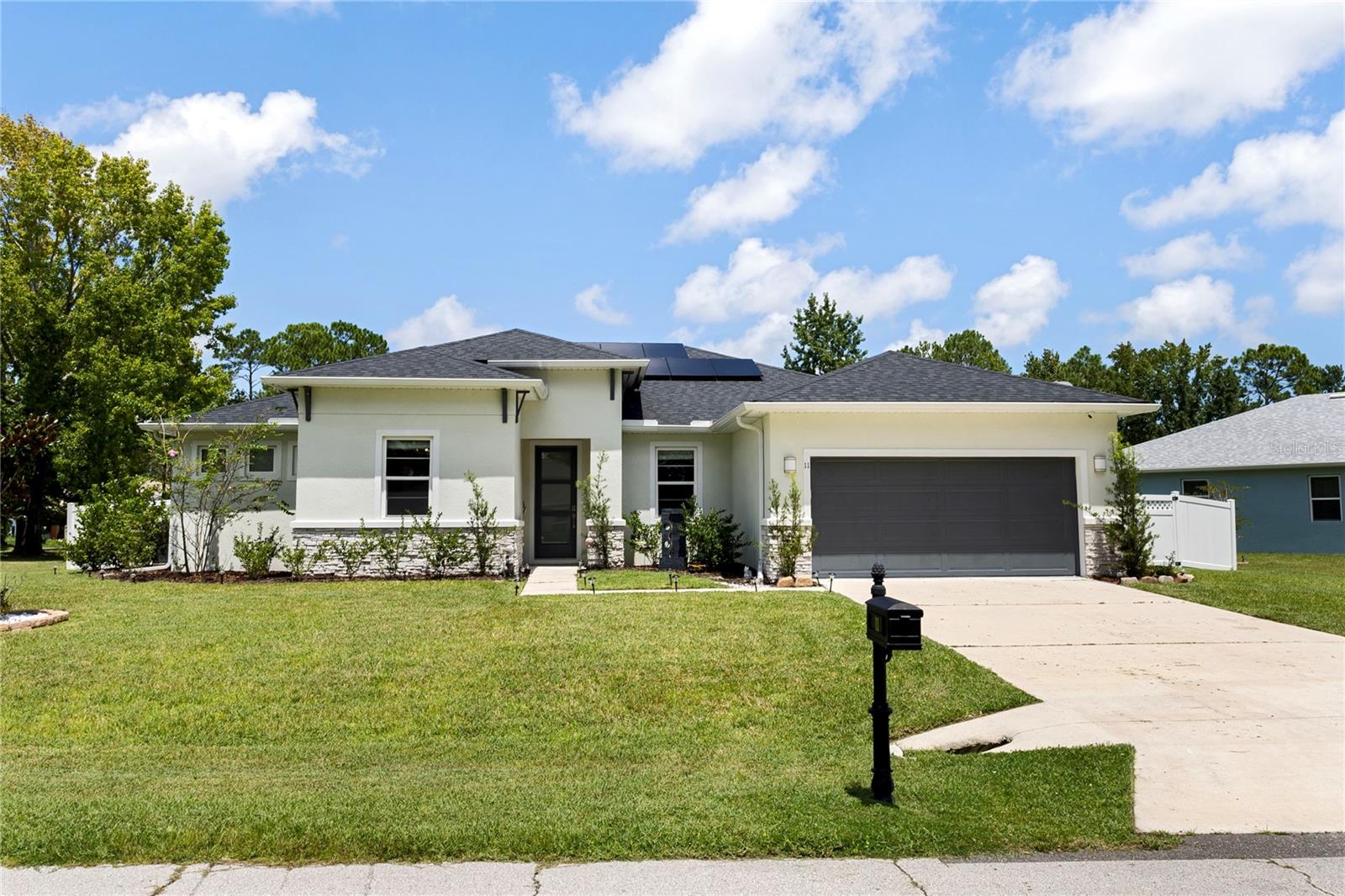 Welcome to this stunning 2022 Palm Coast residence, a move-in ready, solar-powered home that perfectly blends modern design, energy efficiency, and luxurious upgrades. From the moment you step inside, you’ll be captivated by the open, light-filled layout with elegant wood-look porcelain tile flooring, canned lights on dimmers, and surround sound by Definitive Technology in the living area, creating the perfect setting for everyday living and entertaining. The heart of the home is the beautifully designed kitchen, showcasing quartz countertops, a spacious center island, subway tile backsplash, 42-inch shaker cabinets, stainless steel appliances, including a refrigerator that makes craft ice, and a Kinetico water filtration system. The kitchen flows seamlessly into the expansive living area and out through sliding glass doors to the extended lanai with pavers. Complete with a covered grill area and Alexa-commanded bar lights, this space is designed for unforgettable gatherings. The fully fenced backyard with white vinyl fencing and gate offers privacy and plenty of room to enjoy the outdoors. The oversized primary suite is a private retreat with a tray ceiling, a spa-inspired bathroom featuring dual quartz vanities and a walk-in shower, and a custom walk-in closet with built-ins. A private guest suite with its own bathroom provides comfort for visitors, while additional bedrooms offer generous space and double-door closets. An office/flex room adds versatility to fit your lifestyle needs. Smart home technology is found throughout, with Google smart features for convenience and energy-efficient Low-E double-pane windows that bring in natural light while helping reduce utility costs. The home also includes an indoor laundry room with quartz counters, shaker cabinets, sink, and washer and dryer. Set in the desirable Palm Coast area, just minutes from beaches, parks, shopping, and dining, this home delivers the perfect combination of luxury, comfort, and sustainability. Whether you’re looking for a stylish retreat, a family-friendly haven, or an eco-conscious lifestyle, this home checks every box. All information deemed accurate but cannot be guaranteed. Solar panels paid off.
