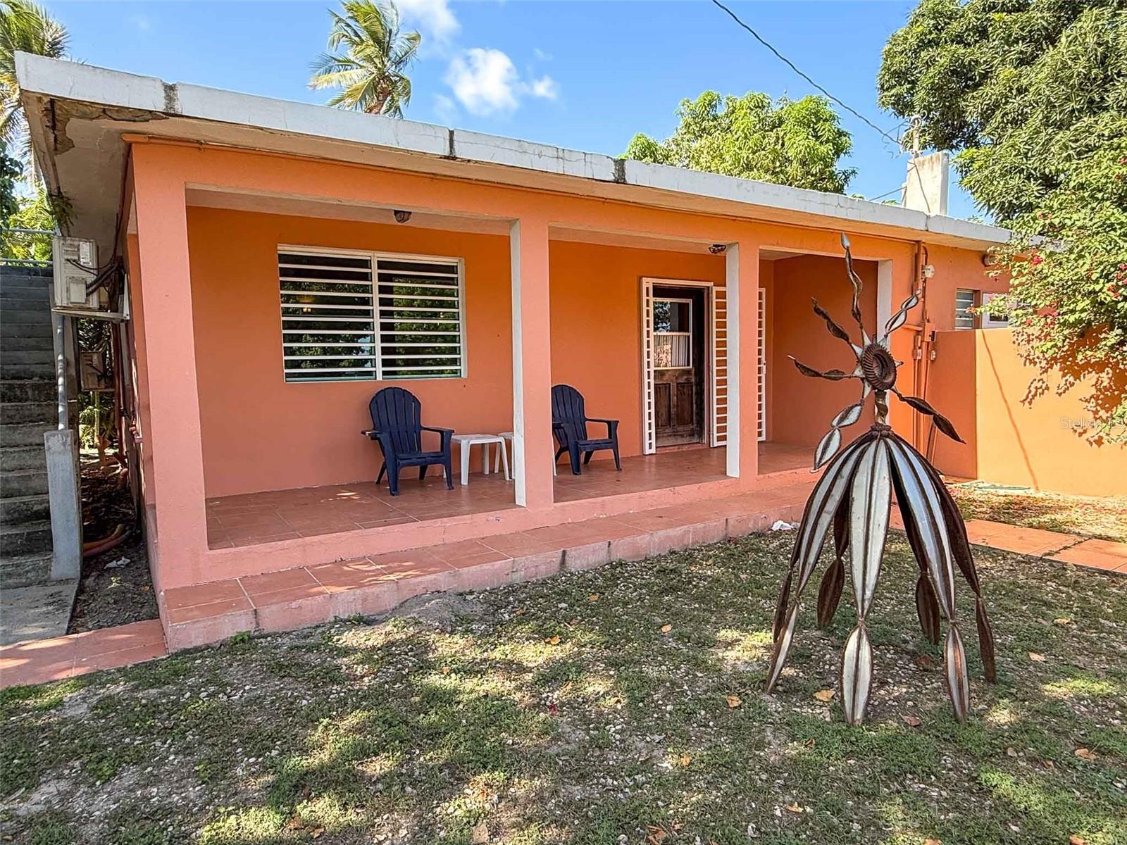 Welcome to the Esperanza Beach House, a rare opportunity to own a turnkey, income-generating property in one of Vieques Island’s most iconic and desirable locations. Set directly on the Malecon in the heart of Esperanza, this unique property offers a front-row seat to the island’s vibrant beachside culture, with immediate access to restaurants, shops, the pier, and the crystal-clear waters of the Caribbean Sea. Whether you’re looking for a personal retreat, an investment opportunity, or a combination of both, this property delivers exceptional flexibility, comfort, and charm.
Built as a solid concrete structure, the home is thoughtfully divided into two separate living units. At the front of the property is a cozy studio apartment, complete with a full bathroom, space for both lounging and dining, and a charming patio overlooking the ocean. This inviting space is perfect for guests or renters and features an umbrella-shaded outdoor table that’s ideal for sipping coffee while watching the sunrise over the sea. A concrete staircase leads to the rooftop, which offers breathtaking panoramic views of the Caribbean. This expansive space presents an incredible opportunity to create a rooftop terrace, lounge area, or even additional living quarters, all framed by endless blue skies and ocean breezes.
The main unit is equally impressive, offering three spacious bedrooms, each with its own ensuite bathroom. Two of the bedrooms feature king-sized beds, while the third is outfitted with twin beds, making the home adaptable for families, couples, or groups. Each bedroom is equipped with air conditioning and glass louvered windows, inviting in natural light and cooling trade winds. The open-concept living room, dining area, and kitchen provide the perfect setting for entertaining or relaxing after a day at the beach. The kitchen is highlighted by a decorative cobalt blue tile countertop and center island, while glass French doors open onto a covered wooden deck at the back of the home—an ideal spot for outdoor dining or gatherings under the palms. Beyond the deck, a concrete path leads through a tropical garden to a storage building that also houses a laundry area.
Located just steps from the beach, this property is a prime base for exploring the best of Vieques. Snorkel around nearby Cayo de Afuera, take in the views from the long pier to the east, or embark on a guided night tour of the world-famous Bioluminescent Bay, conveniently located close by. With a strong rental history and established appeal as a vacation destination, the Esperanza Beach House is a proven performer in Vieques’ thriving tourism market. The island draws over a million visitors annually, with hundreds of thousands seeking out the natural beauty, warm community, and laid-back lifestyle that Esperanza delivers in abundance.
This is a property that truly embodies the Caribbean dream, of sun-soaked days, warm nights, and the sound of the sea just beyond your doorstep. Whether you envision it as your primary home, seasonal getaway, or a high-performing short-term rental, the Esperanza Beach House offers a lifestyle and investment opportunity rarely found on the market.