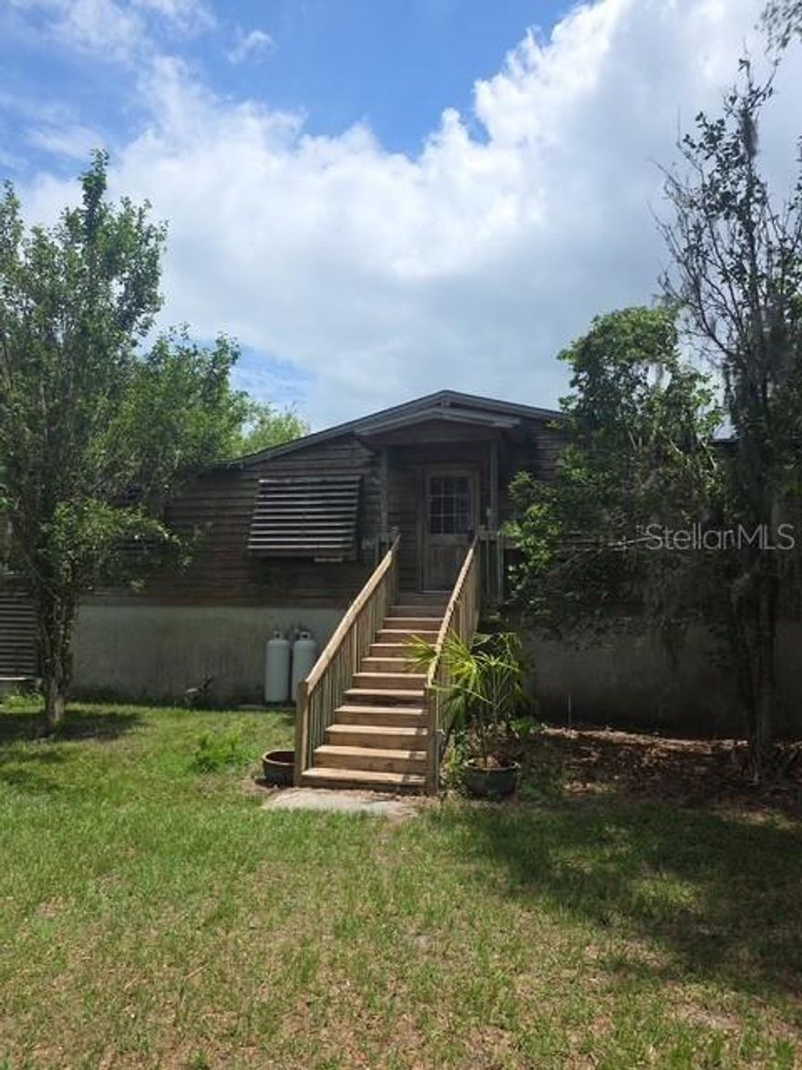 Located in Groveland, this is far from your ordinary mobile home! Nestled on 30 private acres, this unique property offers the perfect blend of functionality, privacy, and outdoor living. Approximately 29 acres consist of scenic wetlands filled with beautiful cypress trees, while the home and all improvements are situated on the one high and dry acre meaning no flood insurance is required.  The property features a deep-water well housed in a dedicated well house with freeze protection, providing crystal-clear drinking water with no staining to sinks, showers, or toilets. The home is set on a solid block foundation with an impressive 88-inch crawl space, allowing easy access to plumbing and electrical systems. The crawl space also includes drainage, a sump pump, lighting, and ample room for use as a workshop or project area.
Exterior upgrades include wood siding with shutters, gutters that drain into a man-made retention pond, covered outdoor storage, and multiple functional outdoor spaces. Inside, the home has been tastefully updated with Hardie Board interior walls, upgraded lighting fixtures, luxury vinyl flooring throughout the common areas and primary bedroom, and updated window blinds. A rustic barn door adds charm and privacy to the French doors leading to the rear deck, which is already equipped with electricity for outdoor lighting and entertainment.

Additional features include a versatile he/she shed previously used as a workout room, a prepared slab with electric and propane connections ideal for an 18-foot above-ground pool or custom firepit area, and an outdoor cooking space complete with a grill, smoker box, electric, lighting, water access, and block walls ready for future expansion.

For RV owners, the property offers full RV hookups and a lift station connected to an oversized septic system. There is also an existing foundation ready for a future pole barn, plus a newer storage shed for all your equipment and storage needs. Fruit trees and clusters of bamboo add even more character and privacy to this one-of-a-kind property.

If you are looking for peaceful country living with room to expand, entertain, and enjoy nature, this property is a must-see!