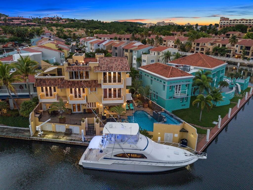An Iconic Waterfront Residence in Isla San Marco, Palmas del Mar.
Nestled on the waterfront with a 90-foot private dock, this three-story masterpiece redefines luxury living. Step onto the open terrace, where sweeping views of the bay and passing yachts create the perfect backdrop for morning coffee, sunset cocktails, or elegant gatherings with friends and family.
The home features four spacious bedrooms, including a primary suite with a private balcony overlooking the bay and boats, offering a serene retreat at the end of the day. Maintain your wellness routine in a private, fully equipped gym, or enjoy cinematic experiences in a state-of-the-art theater with pristine acoustic sound.
The sparkling pool and Jacuzzi provide serene spaces to unwind, entertain, and fully embrace the waterfront lifestyle.
Currently generating $35,000 per month in rental income, this residence combines unparalleled luxury with an exceptional investment opportunity.
With only 40 exclusive residences in this enclave, enjoy unmatched privacy, prestige, and a truly elevated lifestyle reserved for those who appreciate the art of sophisticated living.