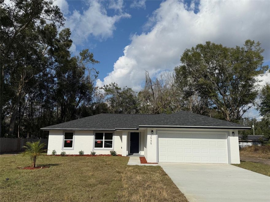 Welcome to this beautifully designed concrete block home in Summerfield, FL, situated on an oversized .30-acre (13,000 sq ft) lot. Featuring an open-concept split floor plan, this 3-bedroom residence offers 1,421 sq ft of living space (1,885 total sq ft) and a spacious 2-car garage. Enjoy modern smart home technology, including a WiFi garage door opener with camera by MyQ and a WiFi AC thermostat by Ironshield for added convenience and efficiency.

The home showcases upscale finishes throughout, including luxury LVP flooring, 5¼” baseboards, two-panel doors, and a thoughtfully designed laundry wash room. The bathrooms feature large-format shower tile and full vanity wall mirrors, while the garage includes a utility sink for added functionality. Exterior details include 24” roof eave overhangs and a professionally installed landscape package with flower beds and a palm tree.

The chef’s kitchen is the heart of the home, boasting 36” white natural wood shaker cabinets with soft-close hardware, a 5’ island with additional cabinetry, ocean beige granite countertops, and Samsung stainless steel appliances. Highlights include a 36” glass-top electric range with 5 burners, a 6.3-cu-ft air-fry convection oven, perfect for everyday living and entertaining.