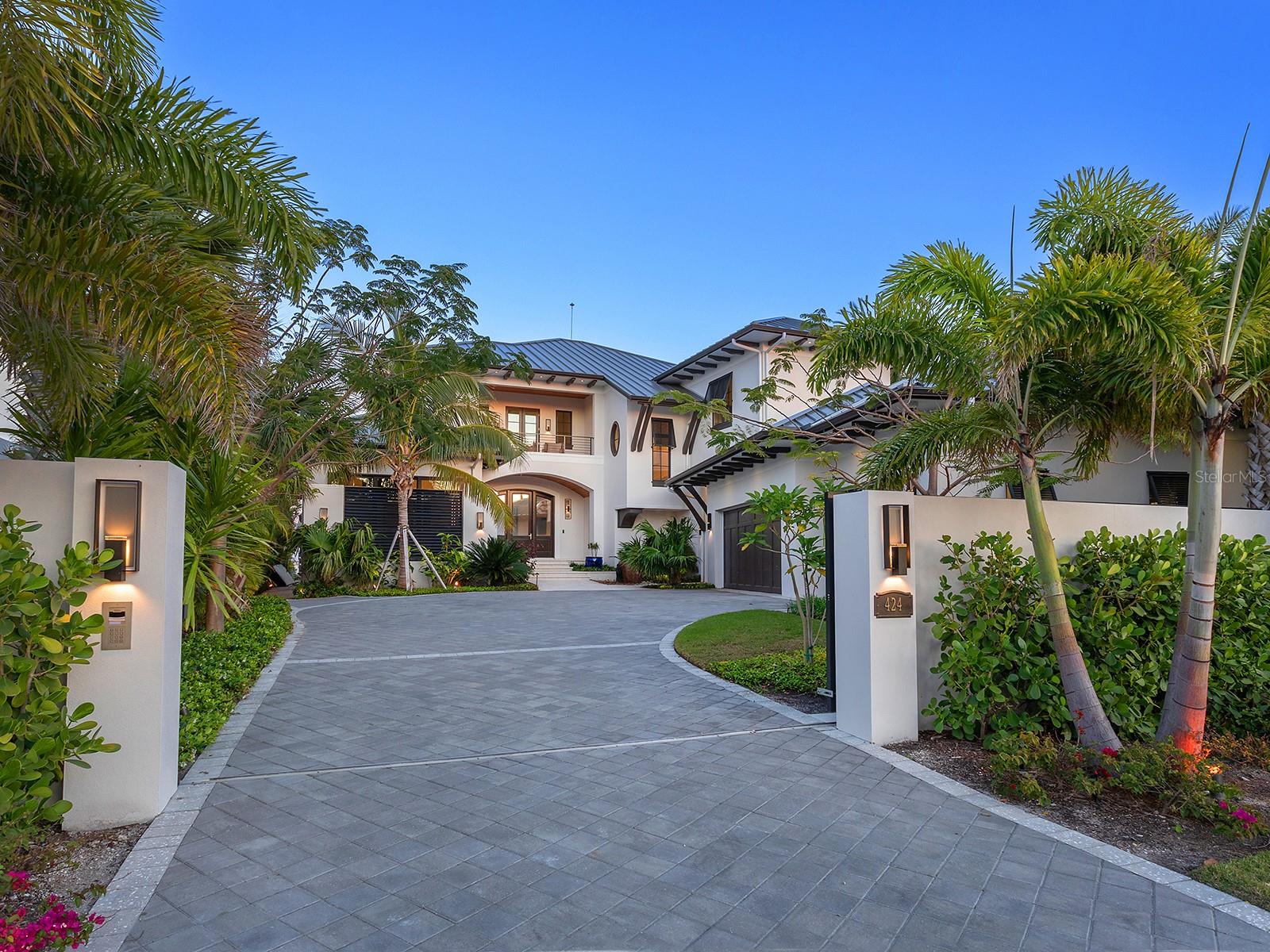 Set against the backdrop of Sarasota's desirable waterfront views, this extraordinary Lido Shores bayfront estate offers the ultimate in luxury living, with easy access to boating, beaches and unmatched views of the Sarasota Skyline, Ringling Bridge and downtown. This is more than a home, it is an icon of West Indies-inspired design, where every detail exudes sophistication and grandeur. From the moment you enter through the private gates, the artistry and precision are undeniable. With over $1 million invested and 2,000 hours dedicated to the creation, this home boasts cutting-edge smart home automation, offering seamless control from anywhere in the world. The custom front door opens to a stunning foyer leading to a great room with a coffered ceiling, media wall, linear fireplace and views of Sarasota Bay. The dining area includes a bar with wine storage and a quartz countertop, flowing into a kitchen with Thermador appliances, a large floating island with quartz waterfall countertop and a walk-in pantry with an extra Bosch refrigerator. The primary suite is a serene retreat with floor-to-ceiling windows, sliders and breathtaking views. It features two custom walk-in closets and a spa-like en-suite bath with floating vanities, a soaking tub, a custom shower with multiple showerheads, and sliders opening to an outdoor shower in a private Zen garden. A striking modern staircase and wine wall lead to an upper-level loft with a wet bar and terrace overlooking the water. A sophisticated office with custom built-ins, plus four well-appointed en-suite bedrooms with custom closets, projector screens and private balconies, ensure luxury throughout. Step into your private paradise, where an infinity-edge pool, sun shelf, in-pool table and cascading spa create a breathtaking resort-style experience. The fully equipped outdoor kitchen, complete with smoker, grill, wok and side burner, makes alfresco dining effortless, while multiple seating areas, a firepit, outdoor shower, and a spiral staircase leading to the upper terrace offer unparalleled relaxation and views. The newer dock is designed for ultimate waterfront living, featuring a 20,000-pound boat lift, jet ski lift, water and power, and a dedicated fishing area with benches and ambient lighting. Just steps from your backyard, Sarasota Bay provides amazing boating waters. The home also includes a three-car garage, two well-appointed laundry rooms, an elevator, a drop zone near the garage and a hidden utility closet. Dedicated to smart home integration, this residence offers unparalleled automation, ensuring complete control wherever you are. This includes advanced automation with Control4, security cameras, a 48-kilowatt generator and a 20-kilowatt battery backup, a high-end audio-visual system, automated shades, circadian lighting, an outdoor theater, app-controlled pool and sprinkler systems, Wi-Fi-enabled appliances, EV charger prewiring, Starlink backup internet, motion-activated lights and voice control through Josh AI. Lido Shores is one of Sarasota’s sought after and architecturally significant communities offering exclusive access to the northern end of Lido Beach. Residents enjoy amenities like a community beach and proximity to nearby attractions such as St. Armands Circle, City Island, Longboat Key and is minutes from downtown Sarasota. This estate is an architectural triumph designed for sophisticated entertaining and extraordinarily comfortable waterfront living.