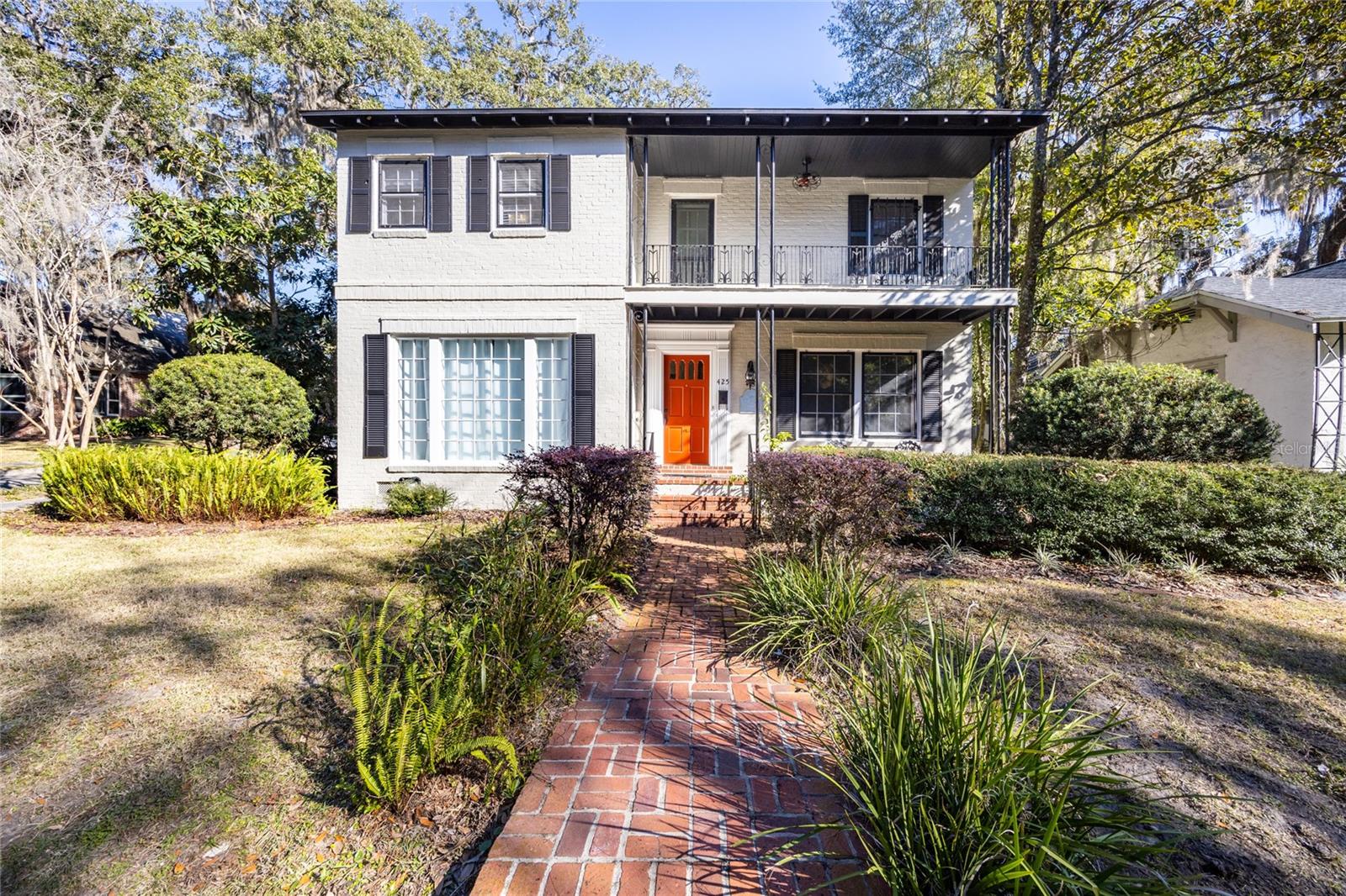 Welcome to The McIntyre House, a real 1938 gem nestled in the heart of the historic district located on the Boulevard overlooking the charming Duck Pond. This amazing property has airbnb bookings through 2026 including multiple football games providing for a steady flow of income. This timeless home seamlessly blends historic character with modern updates, offering a glimpse into the past while catering to today’s lifestyle. From the moment you approach, the McIntyre House enchants with its brick walkway, inviting front porch, and exquisite molding details framing the front door. The backyard is a private retreat, featuring a shaded courtyard with a wonderful view of a majestic live oak, a concrete patio, decorative block walls, and a natural area complete with a fire pit and planting beds. Whether hosting gatherings or enjoying quiet evenings, this space is perfect for both entertaining and relaxation. A one-car carport adds a touch of practicality to this idyllic setting. Step through the front door into a foyer you will immediately notice the hardwood floors that flow throughout the home. To your left, the spacious living room boasts a large picture window that fills the space with natural light overlooking the Duck Pond, a cozy gas fireplace, and access to the downstairs bedroom. This private retreat includes a separate entrance, an en suite bath with a tub-shower combination, and a linen closet. To the right of the foyer, the formal dining room exudes elegance, framed by beautiful windows that surrounds the space in natural sunlight. A convenient half-bath is located nearby. The kitchen has been thoughtfully opened and remodeled, blending functionality with style. It features upgraded soft-close cabinetry, granite countertops, stainless steel appliances, and a large stainless steel sink. Adjacent to the kitchen is a separate laundry/utility room, complete with a pet-friendly door leading to the courtyard. Upstairs, rich hardwood floors lead to the primary suite, which offers a private entrance to the beautifully remodeled shared bathroom. The bathroom boasts a double vanity with granite countertops, a spacious walk-in shower, a private water closet, and again abundant natural light. Across the hall, the second upstairs bedroom is generously sized, accommodating both a king and queen bed with ease. Lovingly updated while preserving its historical charm, the McIntyre House is a rare opportunity to own a piece of history in one of the most sought-after neighborhoods in Gainesville. Don’t miss the chance to call this remarkable property home.