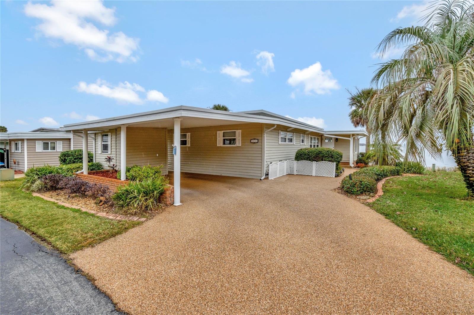 SELLER IS OFFERING A 5,000.00 FLOORING ALLOWANCE! Beautiful View! This 2 bedroom, 2 bathroom manufactured home in Harbor Oaks in Fruitland Park is nestled on Lake Griffin, part of the Harris Chain of Lakes and the 8th largest lake in Florida and home to trophy bass and huge crappie. This home offers a spacious, attractive back deck leading to a dock complete with a boat lift. What a great spot for outdoor dining with friends while taking in the view. The front yard is neatly manicured and has a Chatahoochee River Rock driveway and side walks. This home has a metal roof and a carport and has 2 attached storage rooms. Once inside, notice the open living room and dining room with a built-in china cabinet. The kitchen has a large pass through to the den/office which has lots of windows accenting the fabulous lake scenery. The home has been updated with vinyl siding and insulated glass windows. In the last few years the dock has been refurbished, part of the seawall was rebuilt and a new water heater and garbage dispoal were installed. This home comes partially furnished. The Harbor Oaks community offers a boat ramp, marina, fishing pier, heated swimming pool & spa, shuffleboard, and a friendly, relaxed atmosphere. What a great retreat just waiting for you to make it your own. Harbor Oaks is just 4 miles from The Villages and all they have to offer for entertainment and dining.
