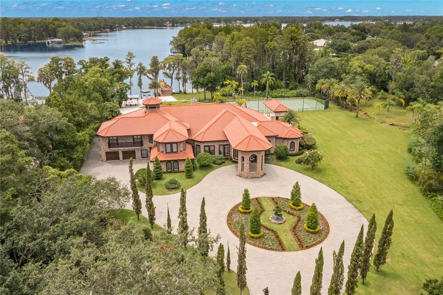 LAKE LIVING AT ITS FINEST! Welcome home to this Hidden Gem! Luxurious 10,000+ sq ft estate located on a beautifully landscaped, 7+ acres equestrian property on the largest private lake in Tampa. Only 10 mins from shopping & top ranked schools & 20 mins from Tampa Airport. This home has everything the most decerning buyer desires including a private white sugary sand beach, boat house with lift, floating dock, 4 jet ski dock, pergola on the beach, pool cabana, outdoor kitchen, gas firepit, pool bath, tennis/basketball & beach volleyball courts with stadium lighting & updated pool & spa. You will be mesmerized from the moment you enter through the private secure gate & drive along the cypress trees. Follow the driveway to a large Porte cochere & step through double front doors into a gorgeous foyer with high wood plank tray ceilings & designer lighting that leads you to an inviting living room with wood flooring, high-end finishes & breathtaking views of the lake & outdoor living space. A large primary suite is located on the right side of the home & features hardwood floors, fireplace, high ceilings, 2 large closets with custom cabinetry, seating area & French doors out to the pool. The updated ensuite features separate vanities with quartz counter tops, tile flooring, large steam shower with rain shower head, separate tub, & water closet. Left of the entrance way you have a large dining room that could easily seat 12 guests & is conveniently located next to the butler pantry and across from the kitchen. In the center of the home is a chef’s kitchen featuring a large center island, quartz & granite counter tops, Dacor appliances, gas range & a wall of cabinets. The kitchen is open to the family room & wet bar with Sub Zero wine fridge, double pull-out drawers & a quartz bar for entertaining. Dine at the breakfast table & enjoy the outdoor views. Through French doors is a study with a built-in workstation with room for 4 chairs & built-in cabinets for storage. The study leads to 2 guest bedrooms with ensuites & walk-in closets. The first guest room has its own private sitting room. A 3rd guest room is located next to the butler pantry & has an ensuite & a walk-in closet. The arts & crafts room has ample cabinetry & granite counters. The laundry room has double washers/dryers, a sink & cabinets with granite counter tops. The gym is next to an indoor sports court with access to a recreation room. The garage includes a fast charge port for electric cars and is connected to a mud room featuring custom shelving for shoes & household items. Upstairs is a large guest bedroom with natural light through windows on 3 sides and an ensuite with double vanities, makeup counter, shower. There is a sleepover room with 3 bunk beds for large parties & family gatherings and it is connected to the movie room. Up a circular stairway you will find a lookout tower offering fantastic views of the entire property. The home features 2 new AC units with separate zones, 25 KW whole house generator, crown molding, hurricane windows, plantation shutters, well water with top of the line maintenance free water treatment system, lake fed irrigation system, & a huge walk-in attic with plenty of storage. A separate 2300 sq ft barn/garage includes a bathroom & 10’ garage doors on both sides & is ideal for car collectors, boats, horses, etc. Outside you can enjoy a stroll or jog around the trail with your own Boardwalk. This home truly has it all. Welcome to Paradise!