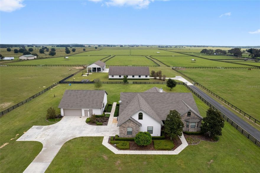 This turnkey 60-acre farm offers tranquility, top-tier amenities, and unmatched convenience. Under 10 minutes to the World Equestrian Center, 5 miles from Live Oak International, and 20 minutes from Ocala’s premier shopping and dining,  The property is fully fenced with five paddocks, two large pastures, and five shade shelters. The immaculate center-aisle barn features 9 stalls, a full bath, feed/tack room, and wash rack. A spacious workshop with open bays and enclosed storage provides ample room for equipment and trailers. The custom three-bedroom home boasts wood floors, crown molding, and a stone fireplace, plus a chef’s kitchen with island seating, pantry, and wine fridge. The bonus room with wet bar and scenic views opens to a peaceful back patio — perfect for relaxing or entertaining. Move-in ready and ideally located, this property offers the best of Florida’s equestrian lifestyle.