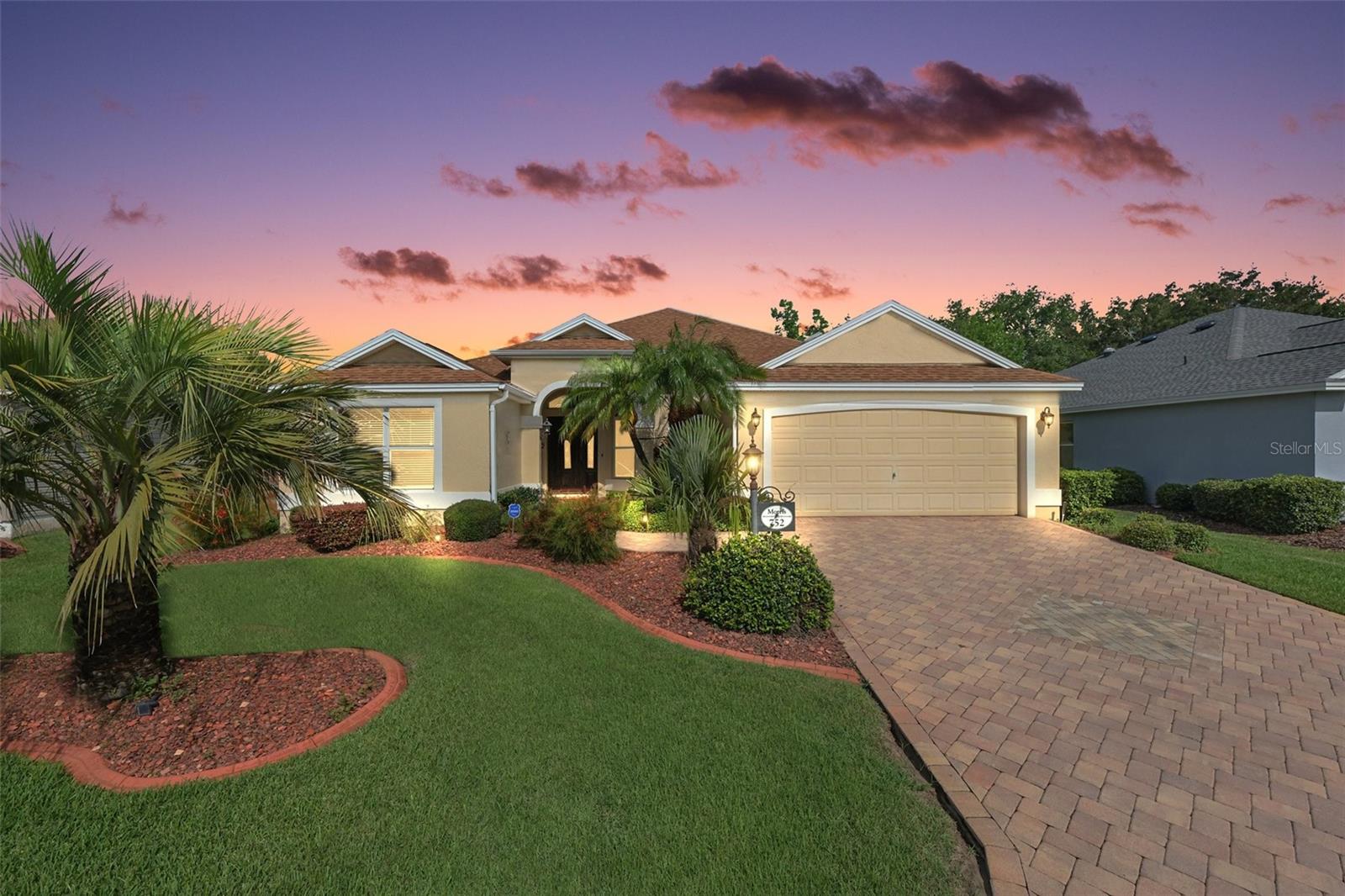GORGEOUS, 3/2 BLOCK and STUCCO Gardenia featuring a FABULOUS ENCLOSED LANAI with MINI SPLIT, EXTENDED BIRDCAGE, and PRIVACY LANDSCAPING in the highly sought after village of Caroline! JUST MINUTES to Lake Sumter Landing! As you approach, the EXQUISITE exterior boasts PAVER drive and walk ways, MATURE TROPICAL landscaping with CURBED beds, and FRESH external PAINT(2024). Step through the ELEGANT WOOD front door with LEADED GLASS and an arched transom window, into the GENEROUS foyer featuring HIGH ceilings and TILE flooring. The MAGNIFICENT kitchen is truly a chef’s delight, boasting RICH CHERRY cabinetry, GRANITE countertops, STAINLESS STEEL appliances, built-in PANTRY, EAT-IN breakfast bar, and TILE flooring. The adjacent dinette offers ample NATURAL LIGHT with double windows and large arched transoms. The OPEN CONCEPT floor plan and HIGH VAULTED CEILINGS of the living and dining rooms creates a SPACIOUS and VOLUMINOUS main living area. OPULENT columns grace the dining room. A DOUBLE set of sliding glass doors, from the living room, lead you into the FABULOUS ENCLOSED LANAI with MINI SPLIT, EXTENDED BIRDCAGE, and PRIVACY LANDSCAPING! This FANTASTIC room offers a PLETHORA of FULL PANEL SLIDING DOORS that can easily be opened on cooler days to enjoy the fresh Florida air or remain closed to provide an ADDITIONAL 252sf of LIVING AREA! This SPACIOUS RETREAT is perfect for everything from RELAXING with your morning coffee to ENTERTAINING friends and family - truly an entertainer’s dream and a PRIVATE sanctuary all in one! Back inside, retreat to your luxurious primary suite, boasting HIGH VAULTED ceilings, TWO WALK-IN closets, and sliding glass doors that open to the ENCLOSED LANAI. It’s ensuite bathroom features CHERRY cabinetry, DOUBLE sinks, MAKE-UP vanity, GLASS-ENCLOSED WALK-IN shower with TILE finishes, and a LARGE LINEN closet. A SPLIT FLOOR PLAN, places two additional bedrooms and second bathroom near the front of the house, creating a PRIVATE GUEST WING or QUIET home office area. Bedroom two offers a built-in closet. The second bathroom features TILE floors, CHERRY vanity, TILED tub and shower combination, and a hallway LINEN closet. The third bedroom (no closet) would make a wonderful home office or additional sleeping area. The CENTRALLY LOCATED INTERIOR LAUNDRY ROOM offers WHITE cabinets for additional STORAGE needs, a utility sink, and TILE floors. It leads you into the two-car garage with INTER-LOCKING TILE floors, attic access with stairs, and TRIPLE layered wall shelving for an ABUNDANCE of extra STORAGE! DON’T MISS YOUR OPPORTUNITY to make this GORGEOUS HOME YOUR OWN! The Village of Caroline offers an UNBEATABLE LOCATION - ONLY MINUTES from Lake Sumter Landing - where you’ll find an array of shopping, dining, and nightly entertainment! You’ll also be close to Mallory Hill and Arnold Palmer Country Clubs and Championship Golf Courses. Health enthusiasts will love the proximity to the Lake Miona Regional Recreation Center and Fitness Trail. Also nearby to Coconut Cove Recreation Center; Caroline Neighborhood Pool; additional recreation centers, golf, pickle ball, swimming pools, and more! This home truly is a gem, located in one of the most desirable neighborhoods in The Villages! PLEASE WATCH OUR WALKTHROUGH VIDEO of this AMAZING HOME in a FABULOUS LOCATION and call today to schedule your Private Showing or Virtual Tour!